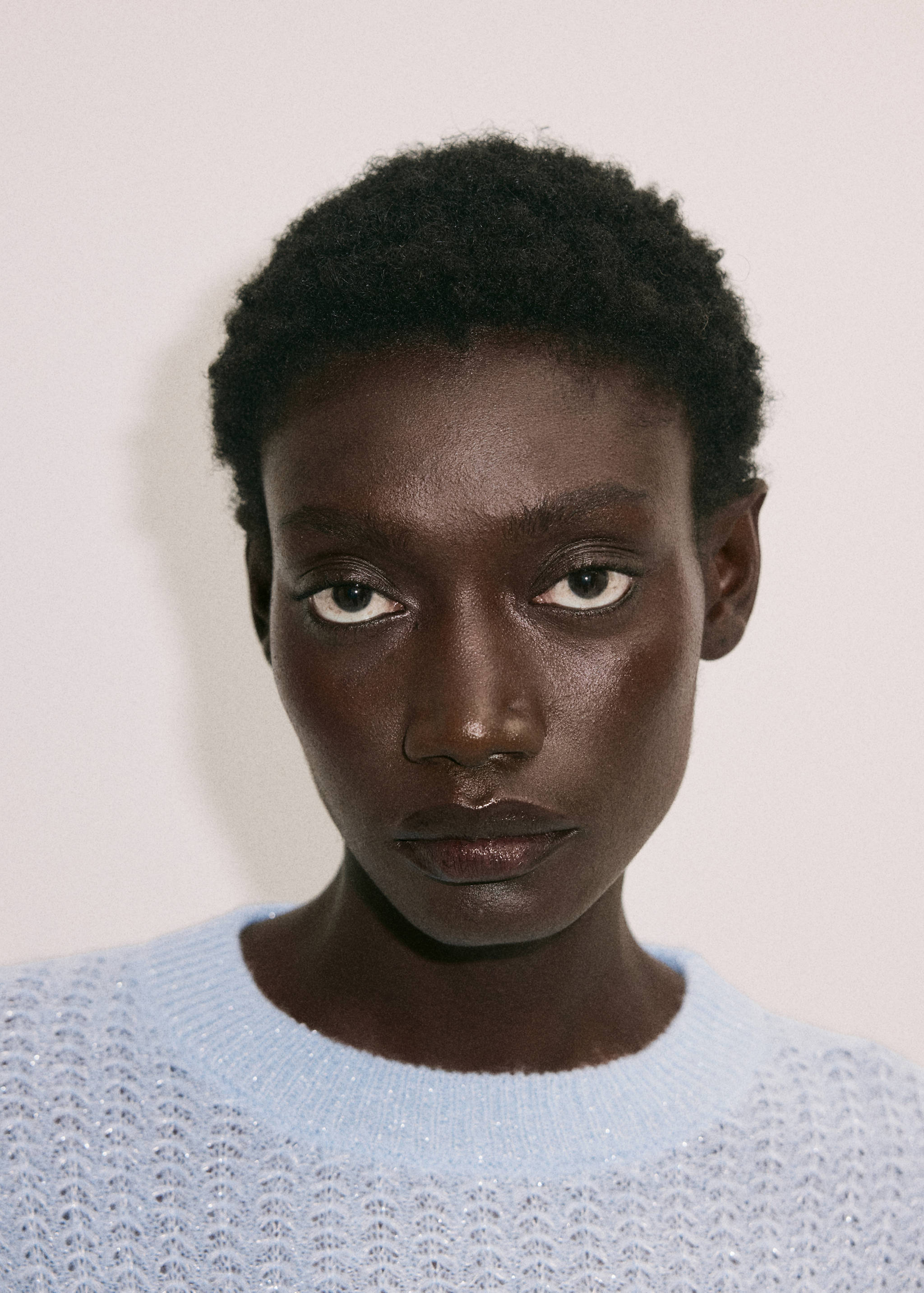 Close-up of a light blue textured knit jumper with a round neckline.