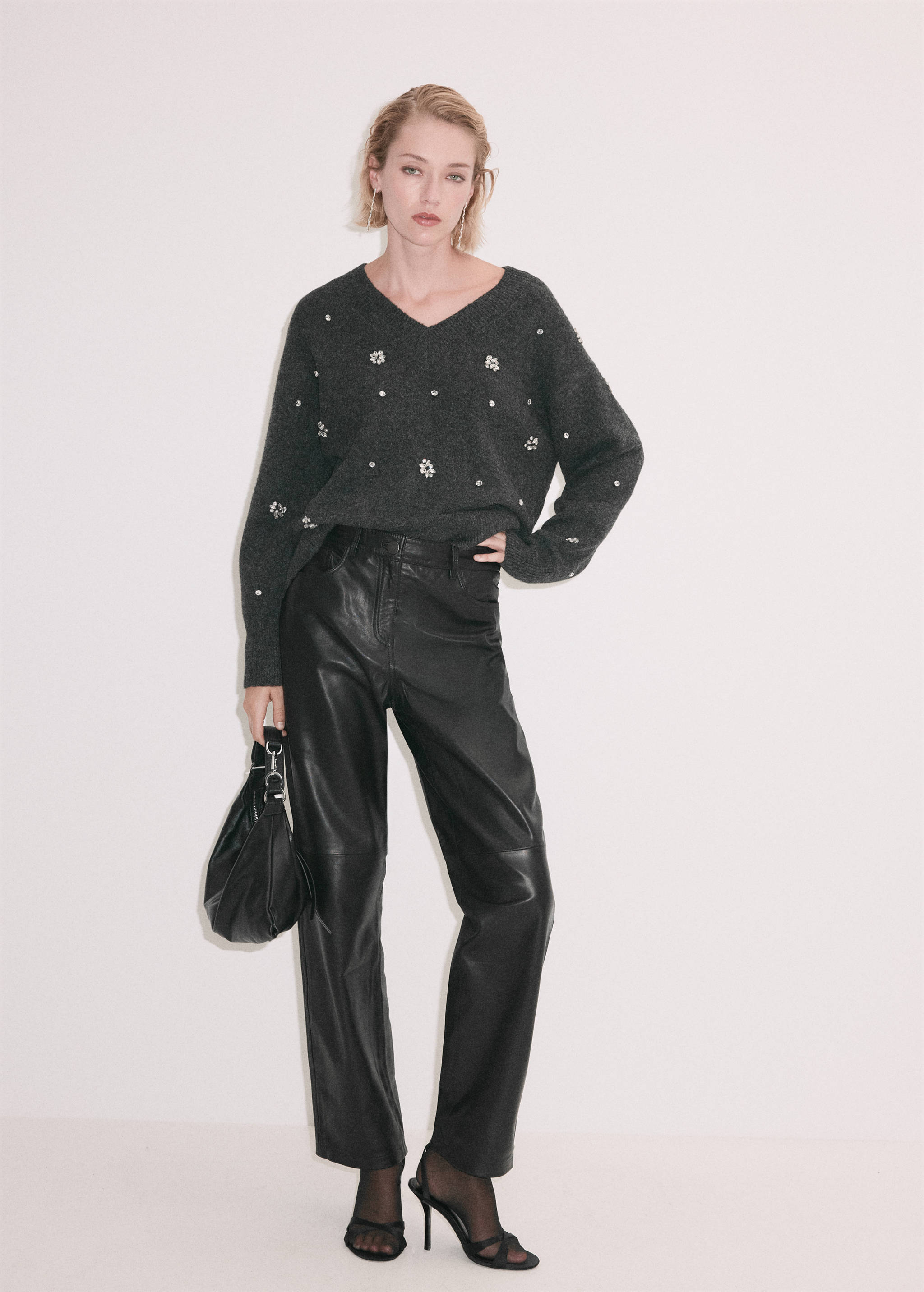 Dark grey V-neck knit jersey with rhinestone embellishments, worn with black leather trousers.
