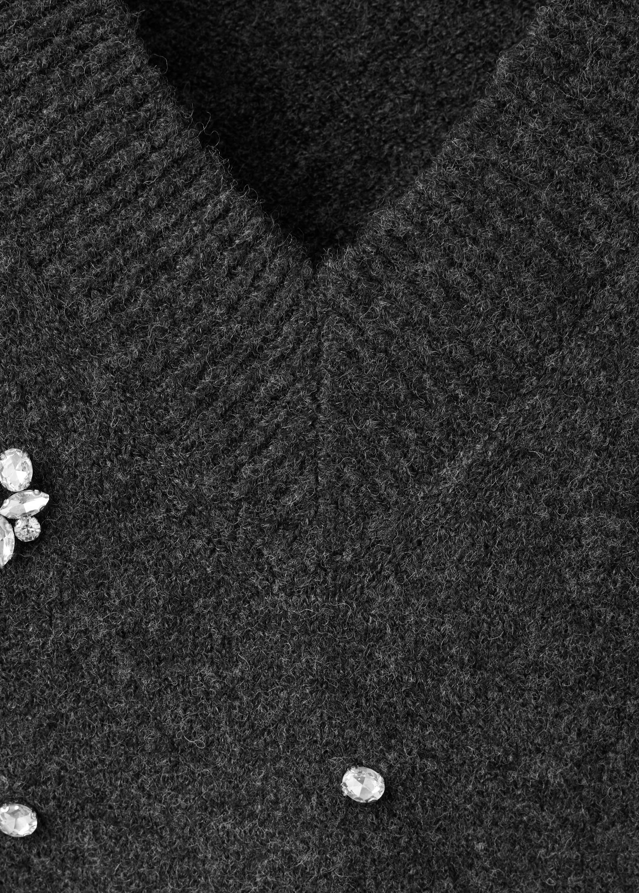 Close-up of a dark grey V-neck jersey with rhinestone embellishments.