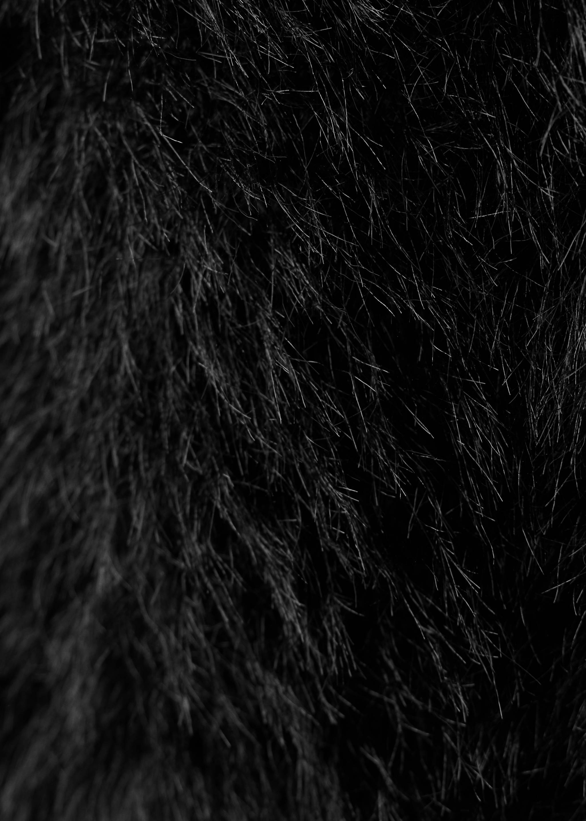 Close-up of black hairy faux-fur knit texture.
