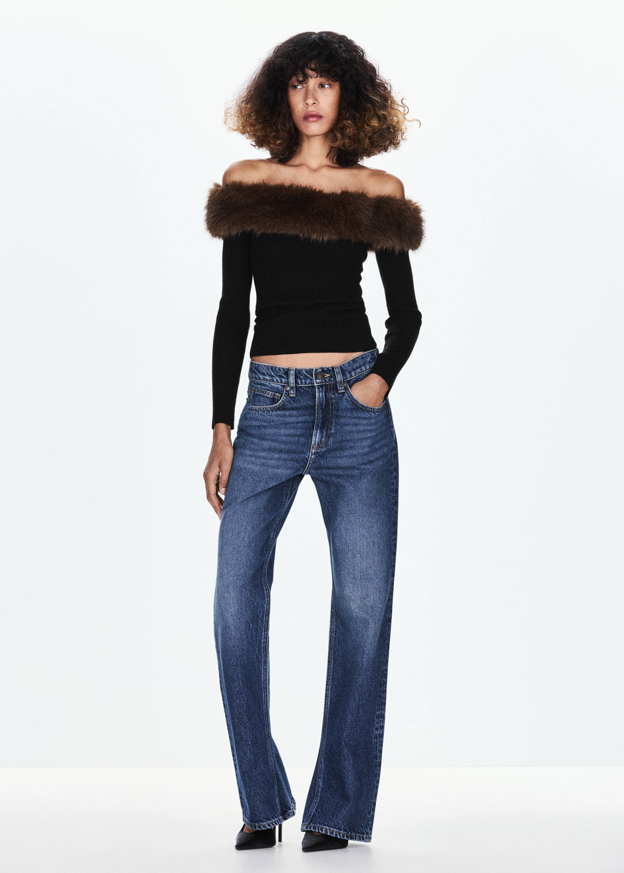 Black knit off-the-shoulder jersey with a brown faux-fur trim, worn with blue jeans.