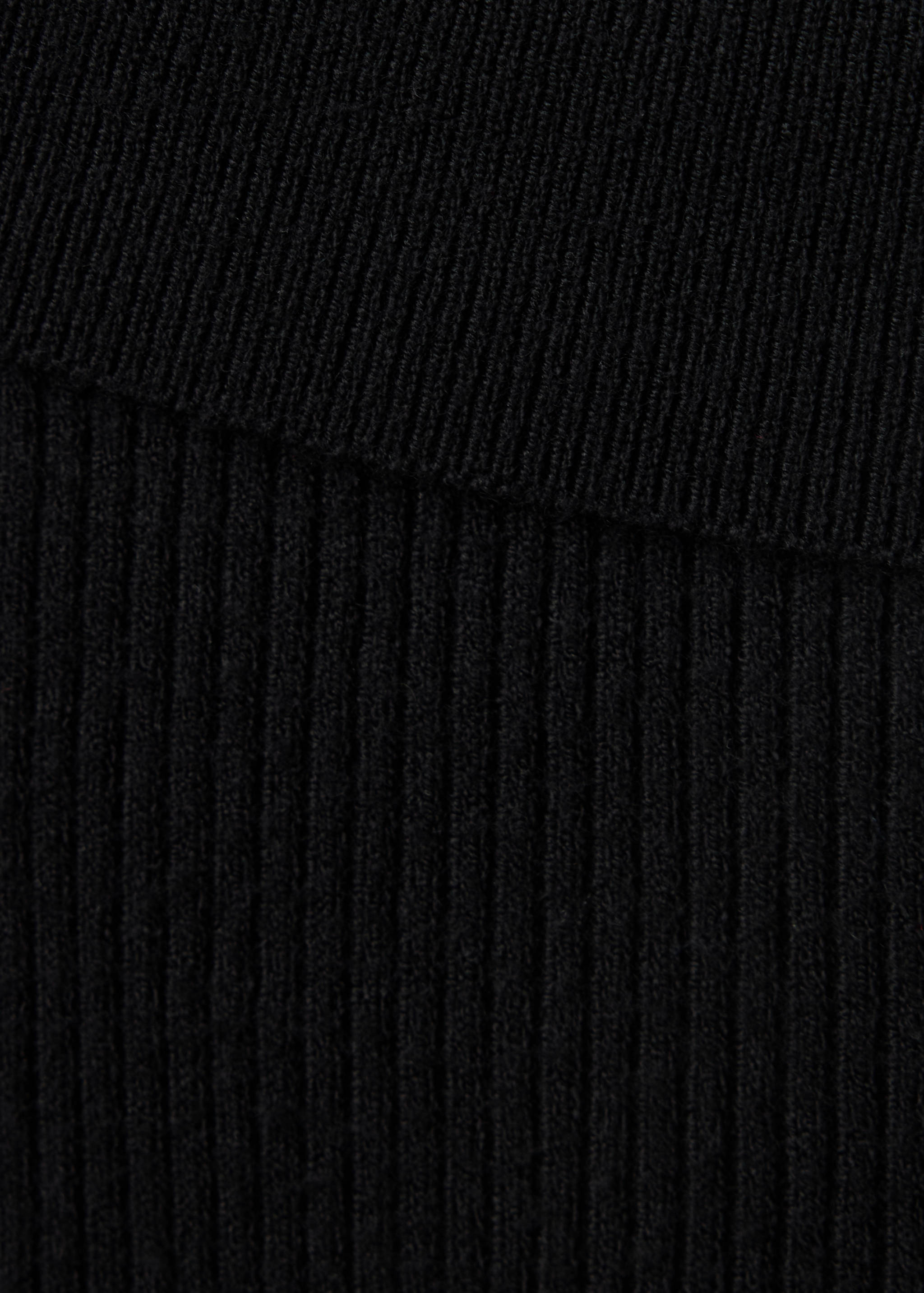Close-up of black sweater fabric showing a fine knit and ribbed texture.