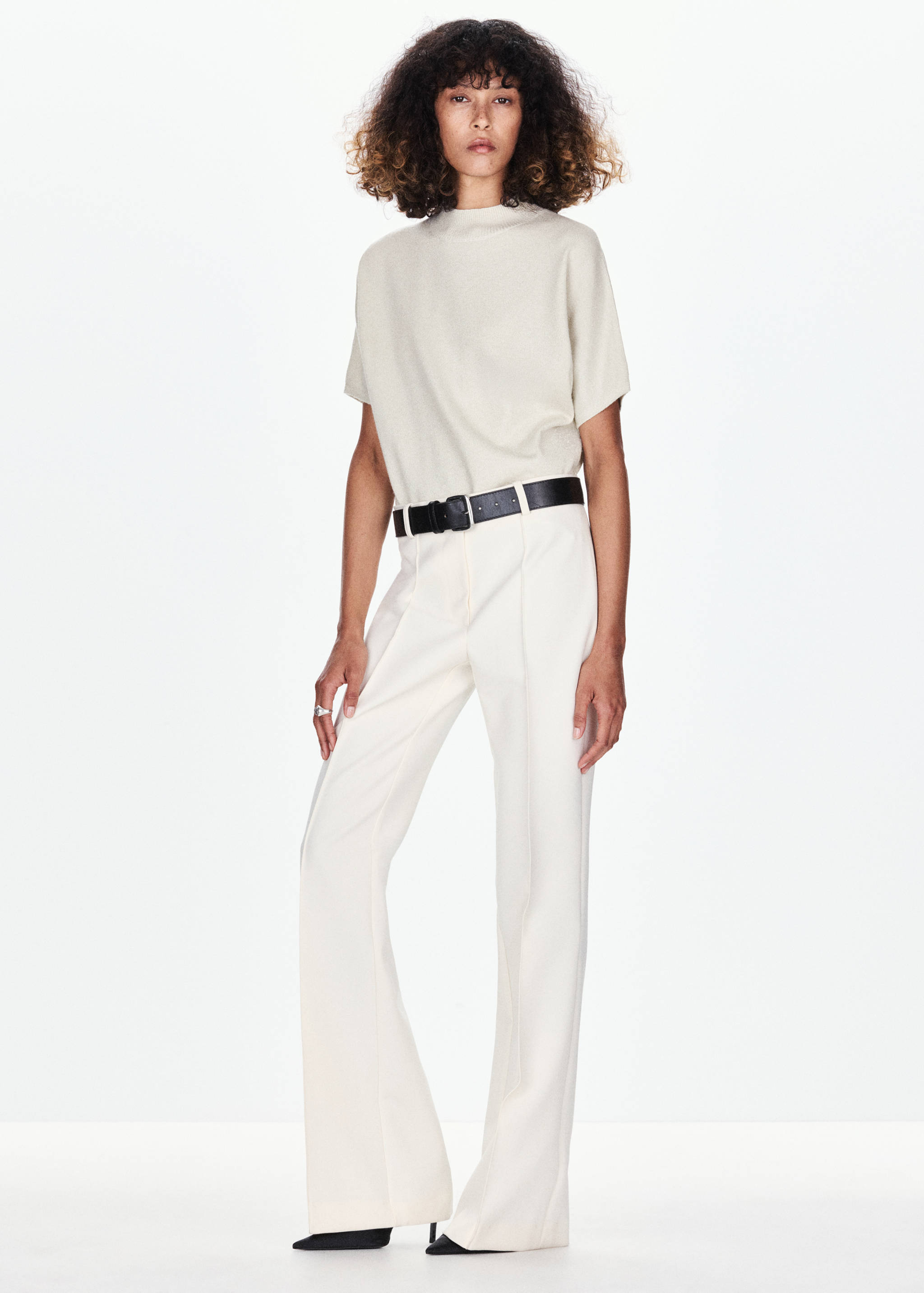 Cream short-sleeved jersey with a mock neck, worn with cream trousers.