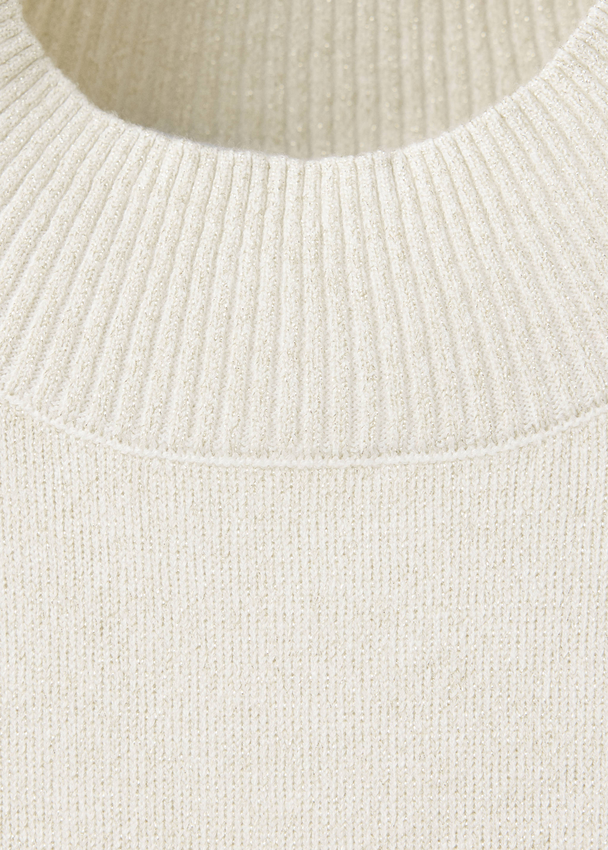 Close-up of an off-white knitted jumper with a ribbed neckline and subtle metallic shimmer.