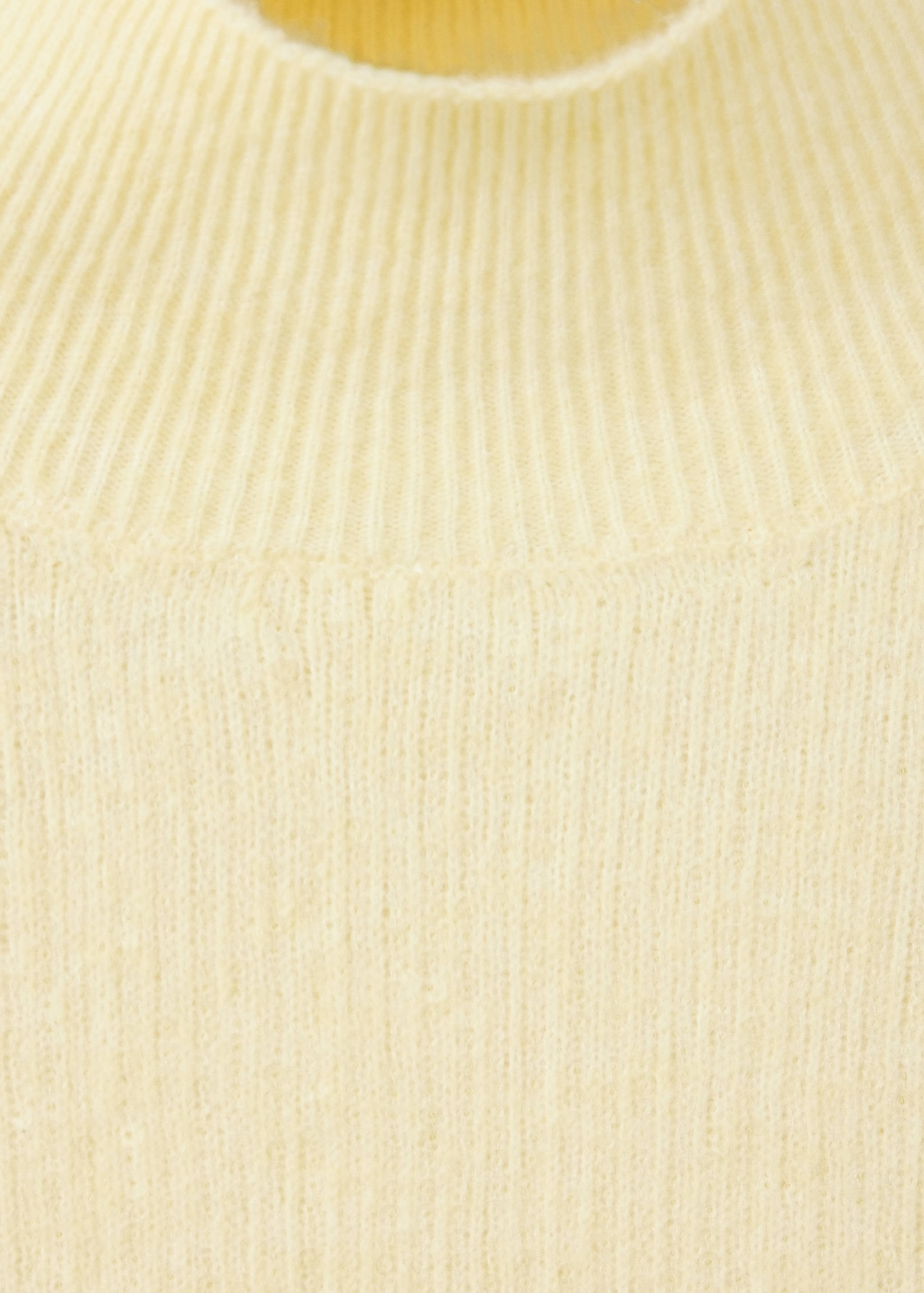 Detalle de jerséis de punto amarillo claro que muestra el cuello alto de canalé.