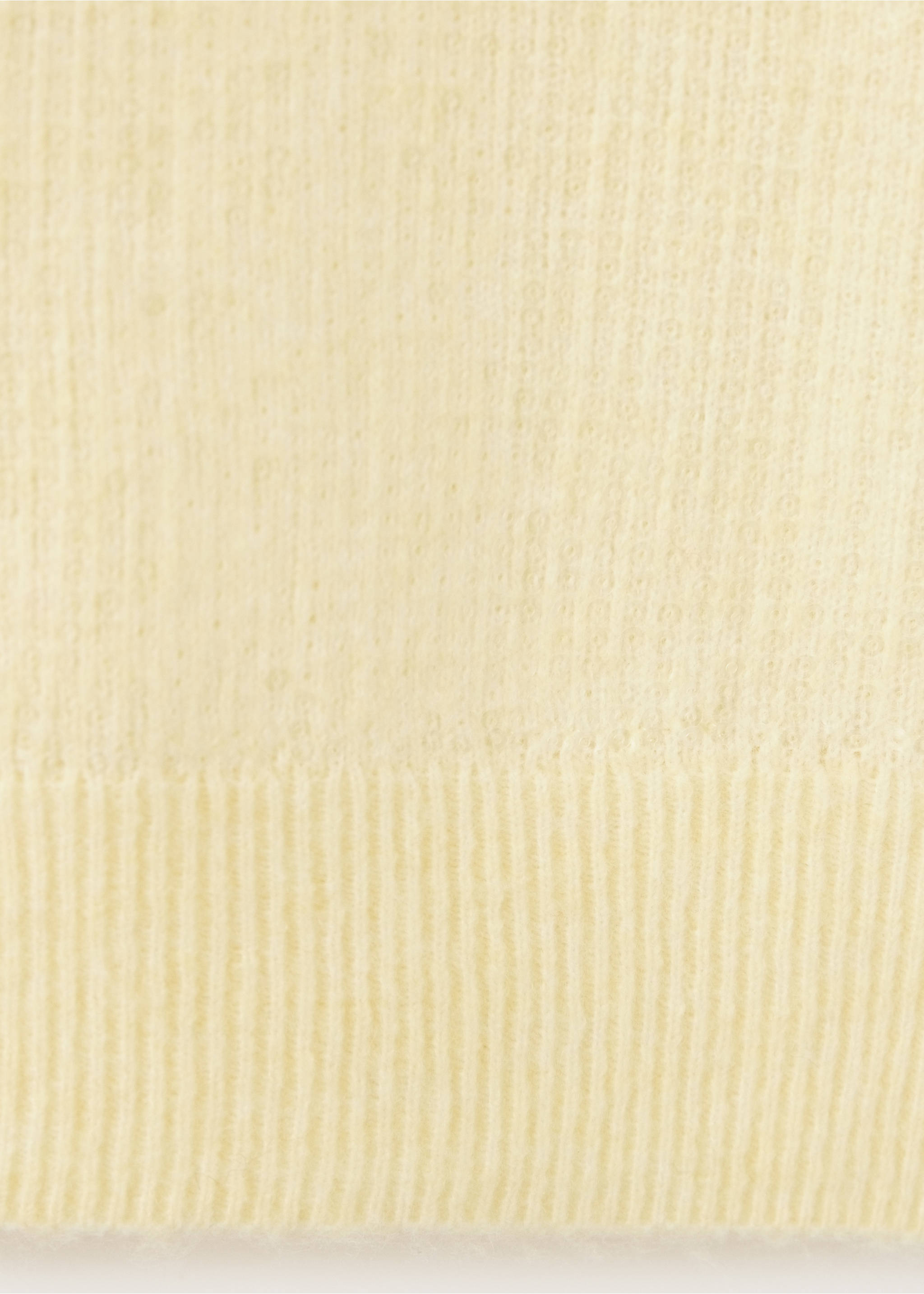 Primer plano de un tejido de punto fino de color amarillo pálido con textura y dobladillo de canalé., Amarillo pastel. Ref: 37009142-00.