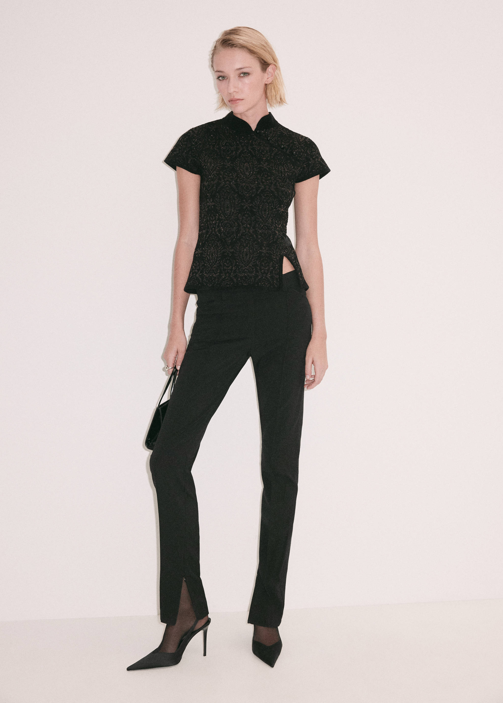 Jersey negro de manga corta con cuello mao y sutil estampado, combinado con pantalones.