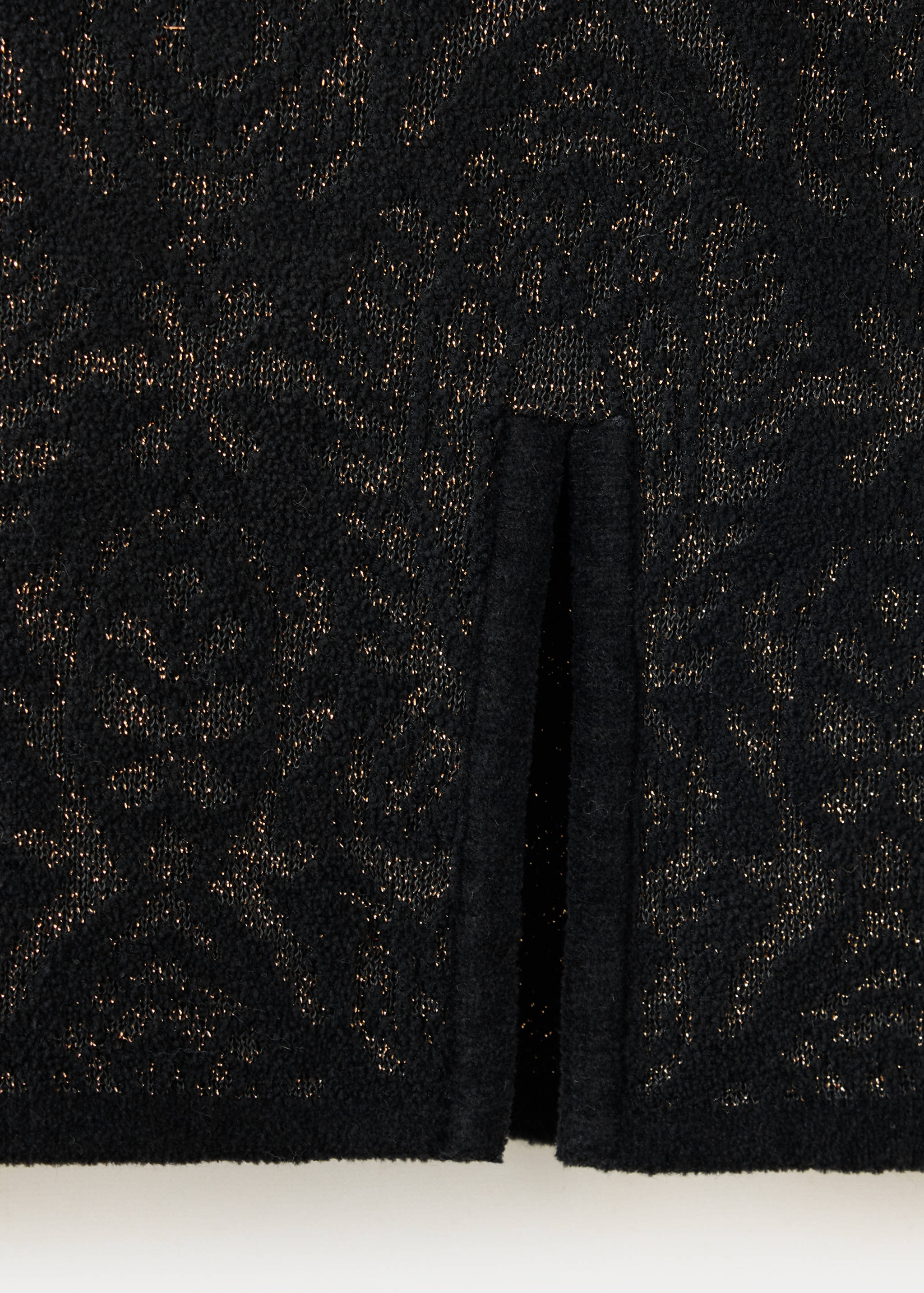 Primer plano de tejido de punto negro con un estampado dorado metalizado.