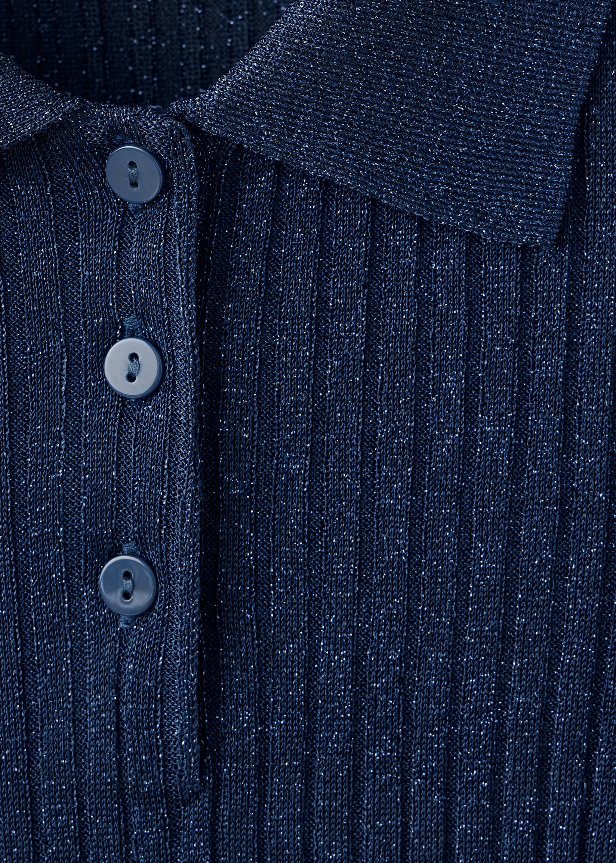Detalle de jersey de punto acanalado metalizado en azul marino que muestra el cuello y la botonera.