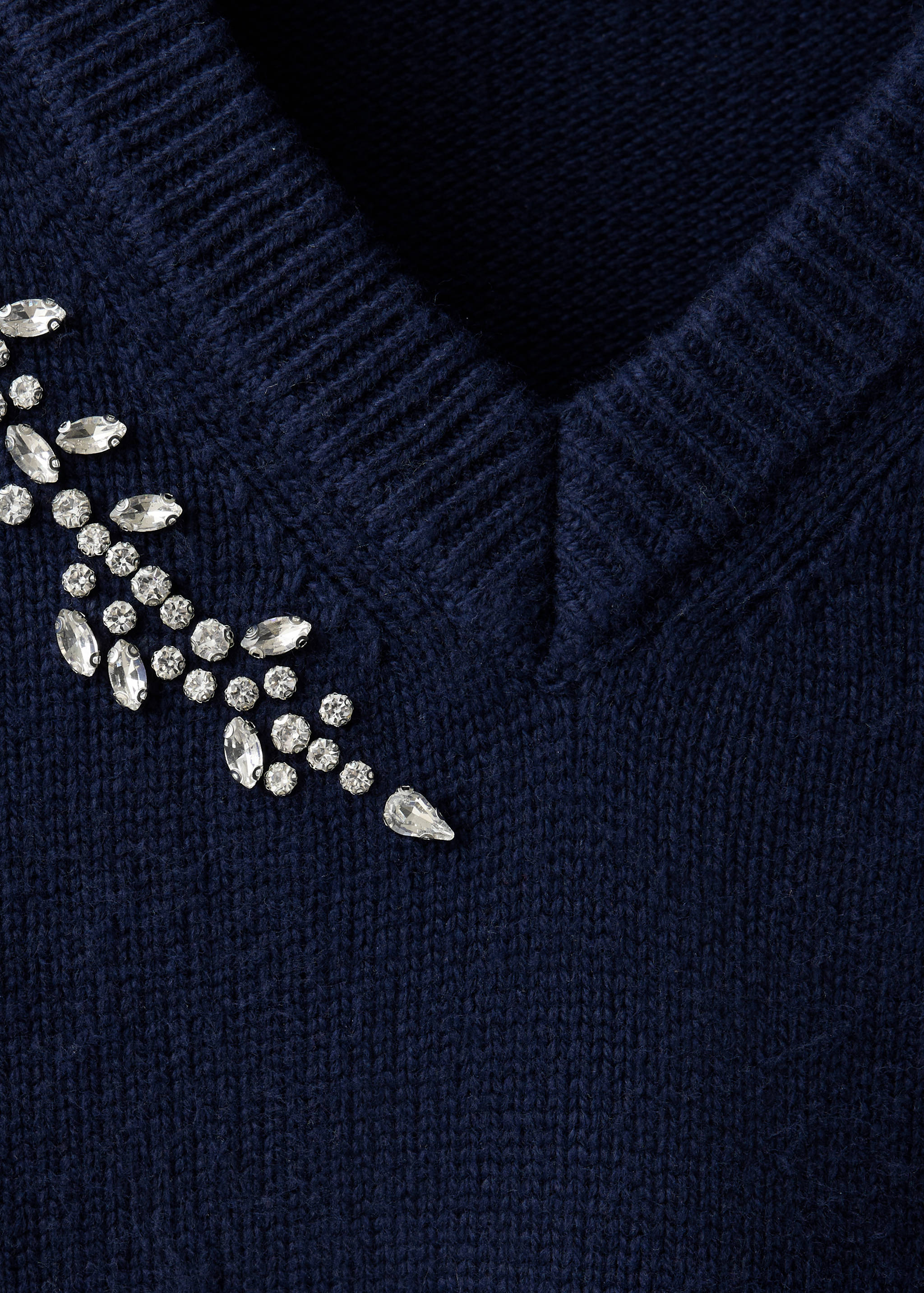 Close-up of a dark blue V-neck knit jumper with crystal embellishments.