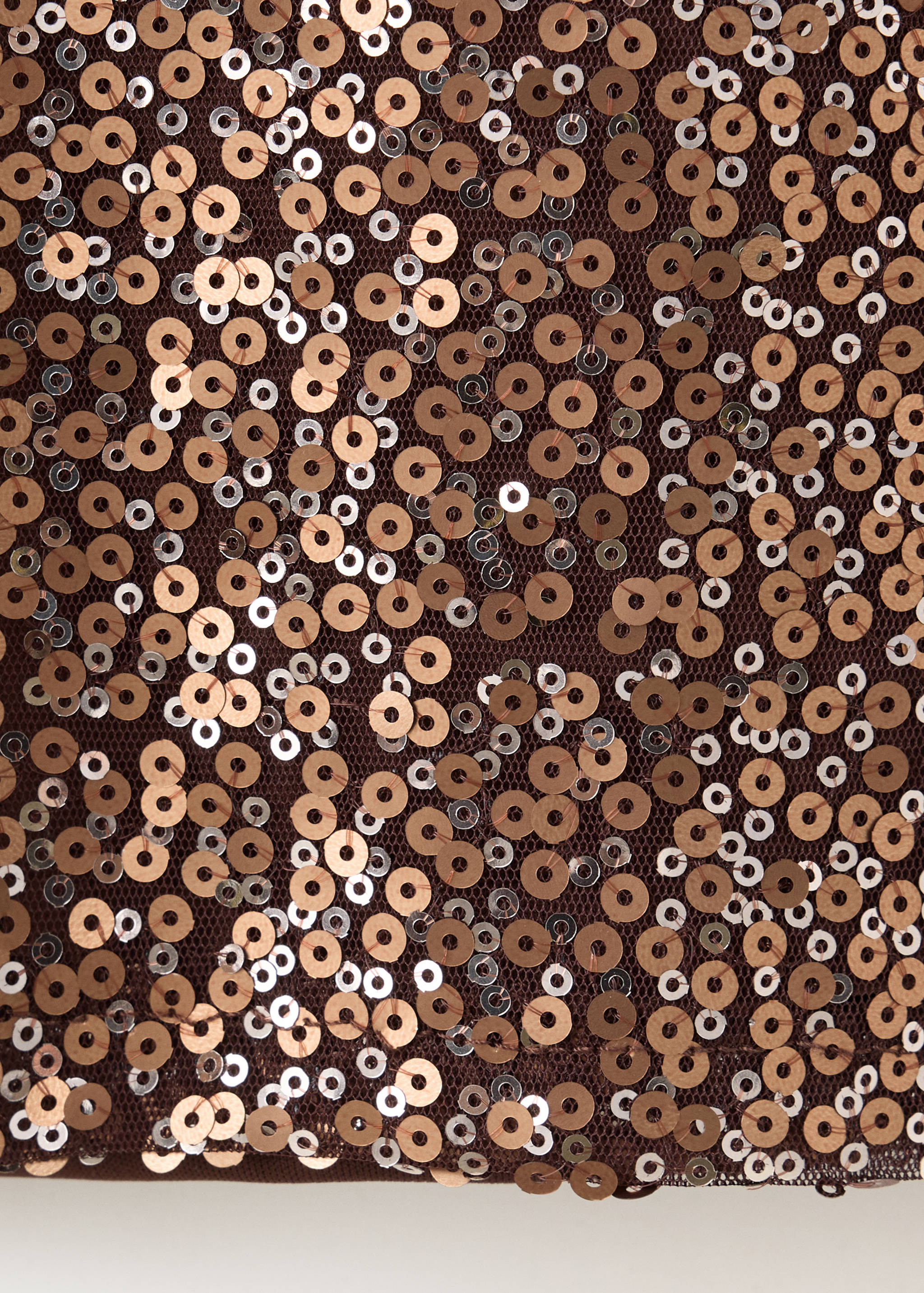 Primer plano del tejido de una camiseta infantil de malla marrón con lentejuelas en tonos bronce y plateado.