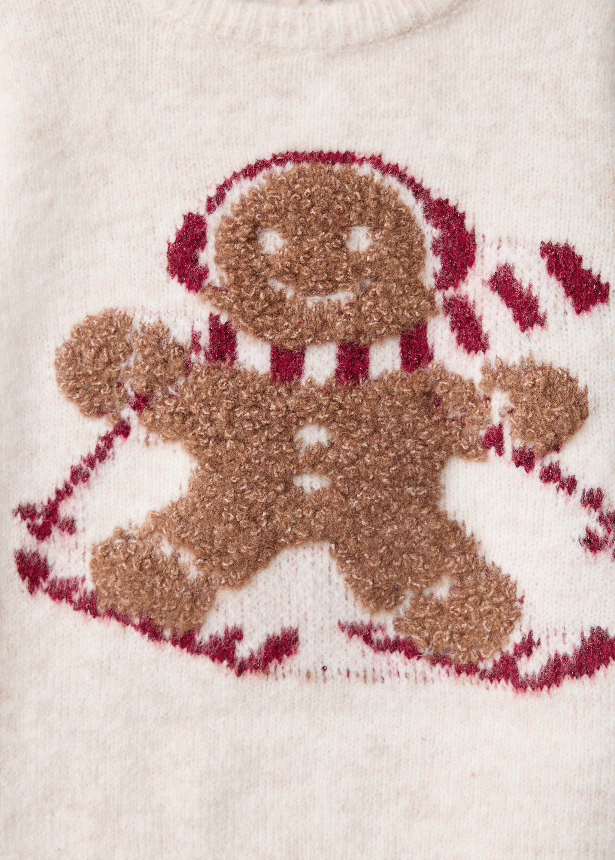 Close-up of a cream jumper with a textured brown gingerbread man graphic.