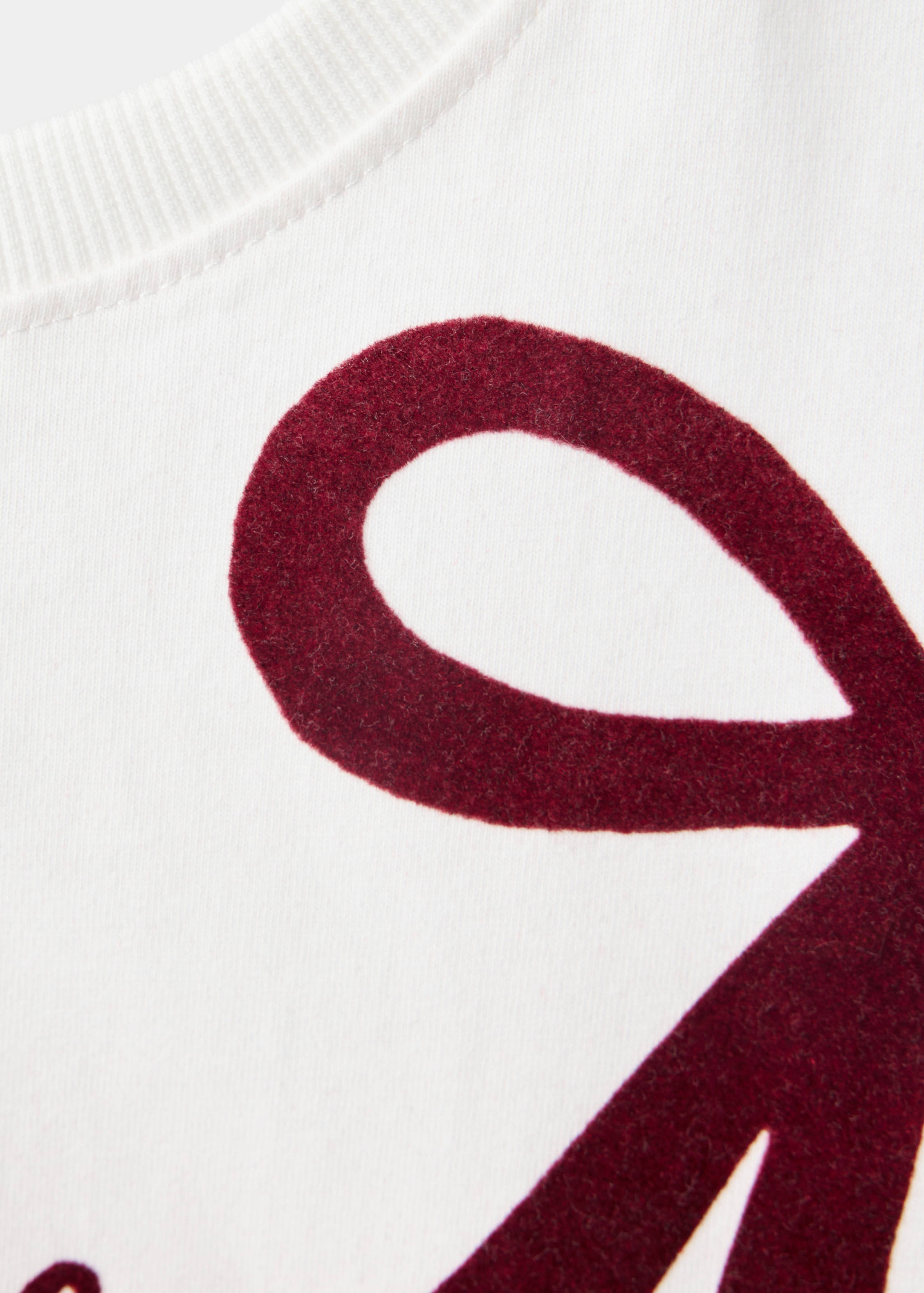 Close-up of a white kids' t-shirt with a textured dark red graphic.