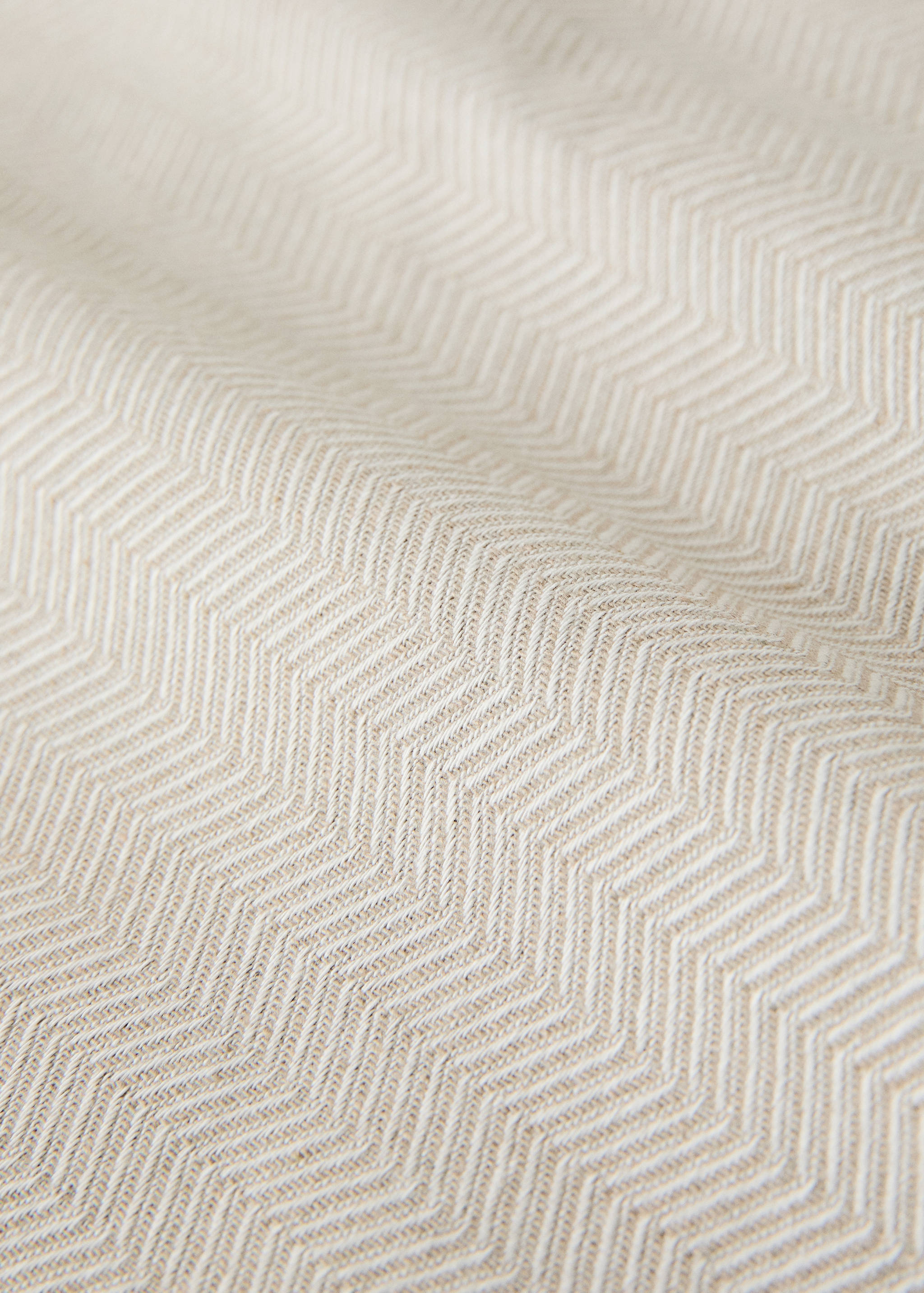 Primer plano de un tejido de espiga en beige y blanco.
