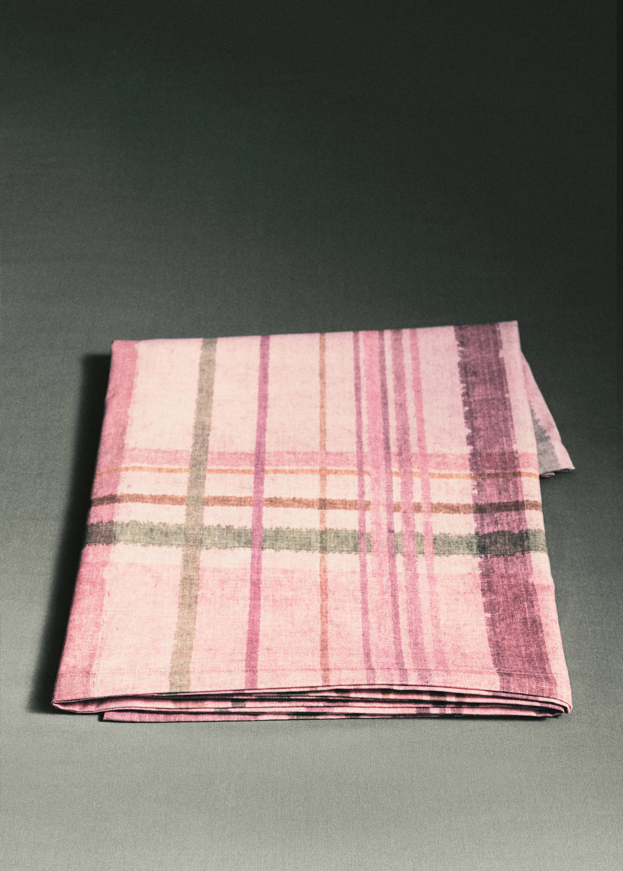 Pink striped tablecloth styled with tableware and a napkin on a table.