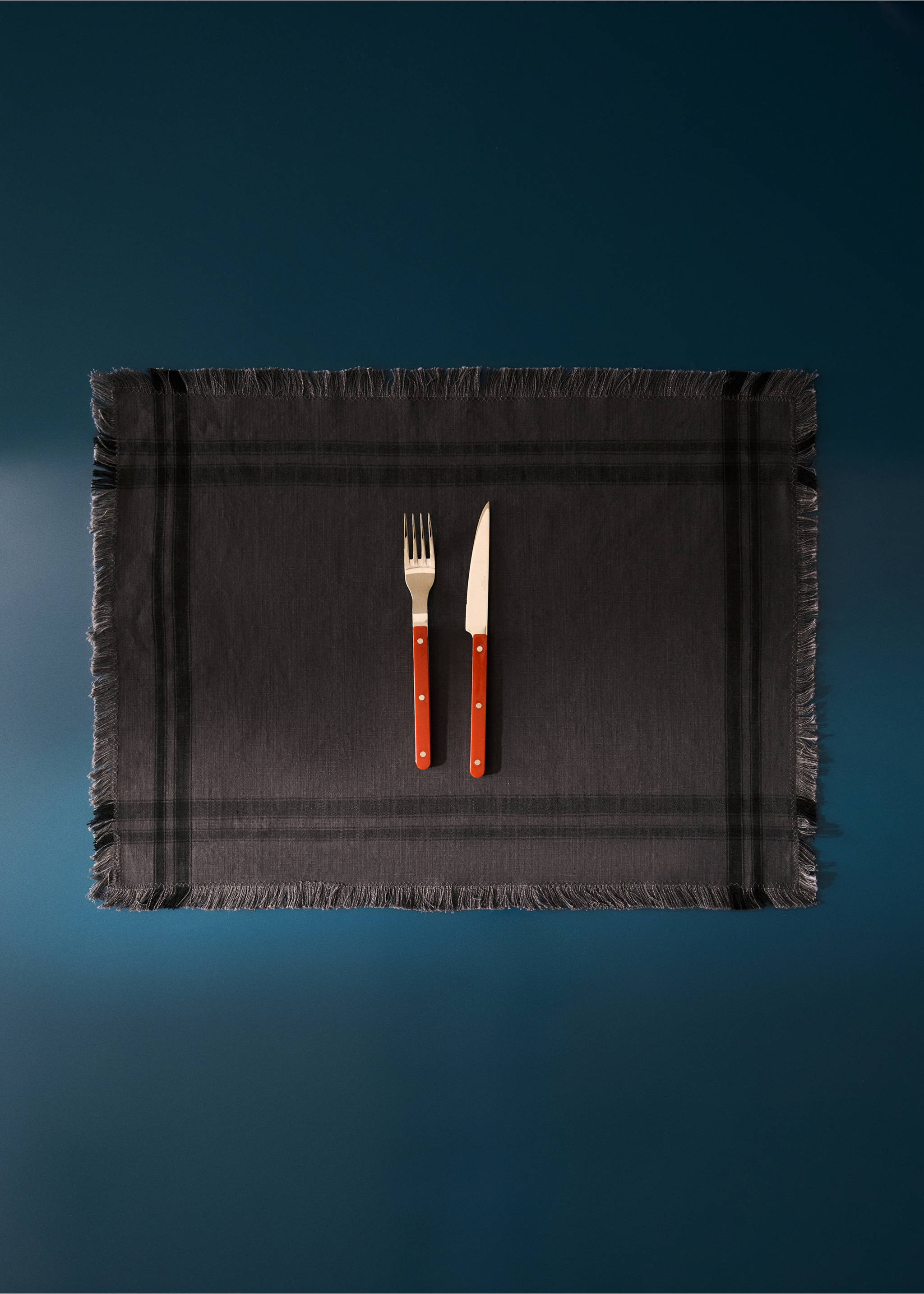 Grey check placemat with fringed edges on a dark surface., Grey. Ref: 37012573-00.