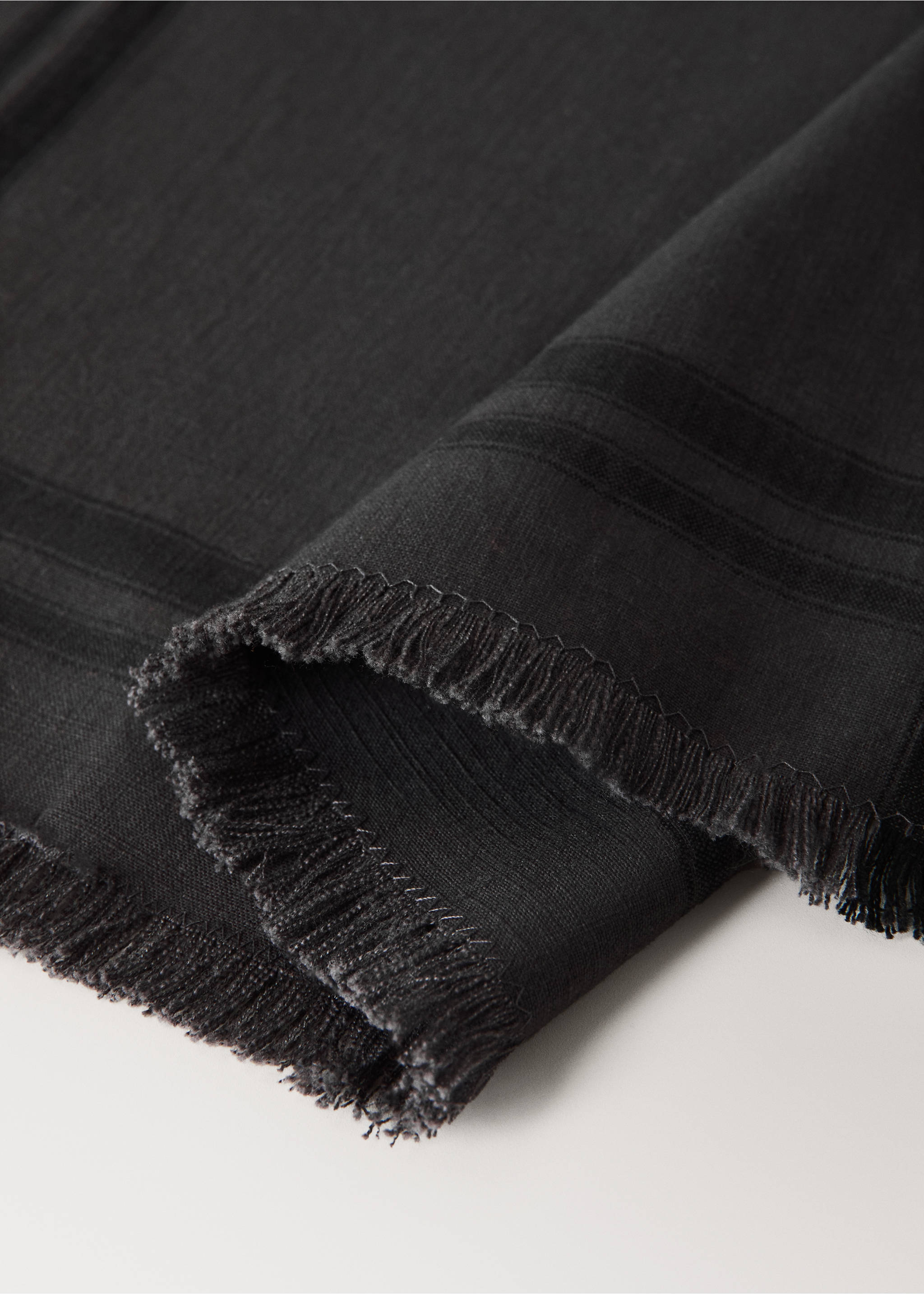Dark grey textured placemat detail with a frayed fringe., Grey. Ref: 37012573-00.
