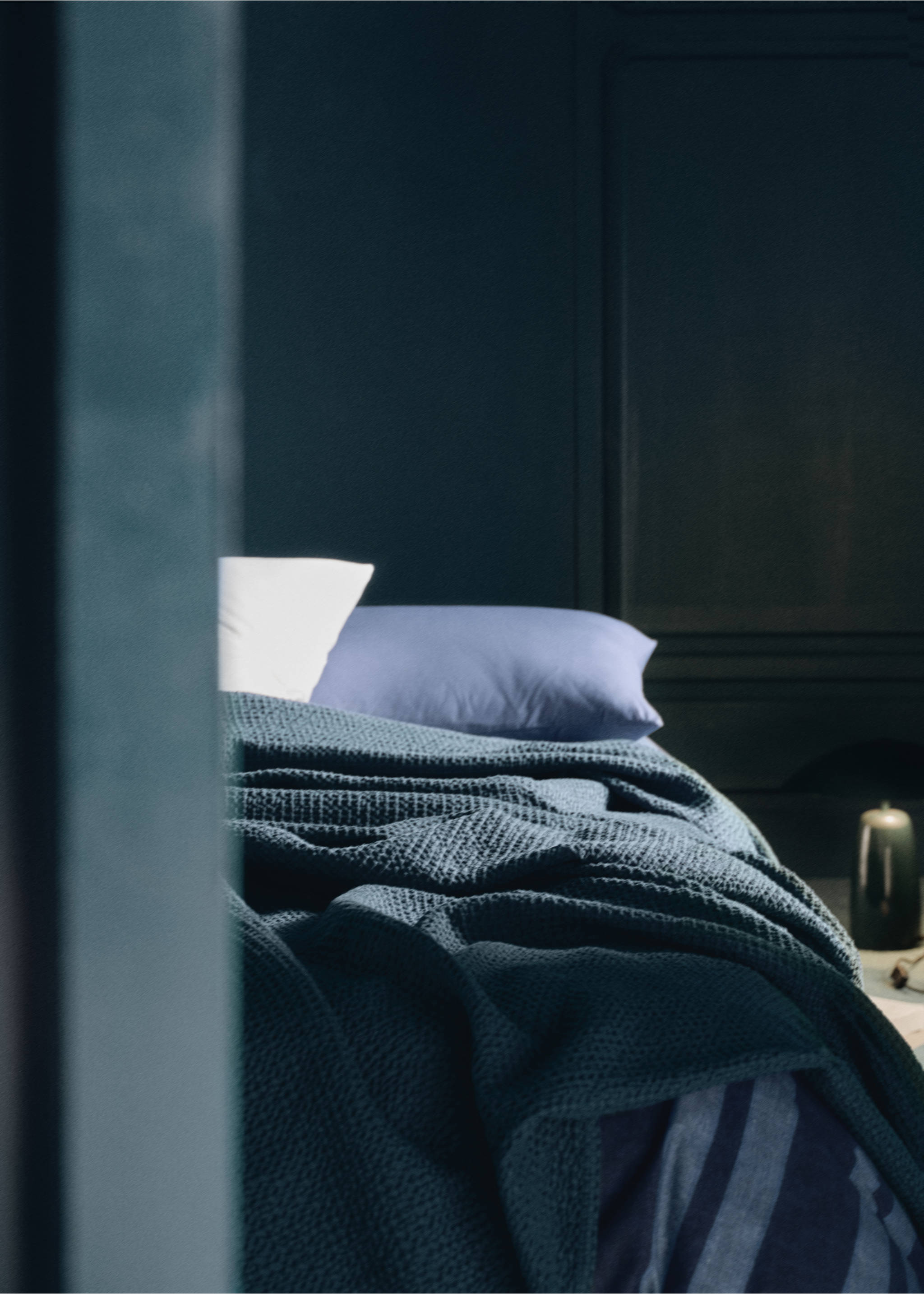 Dark greyish-blue textured duvet cover on a made bed in a dimly lit bedroom., Indigo Blue. Ref: 37012964-00.