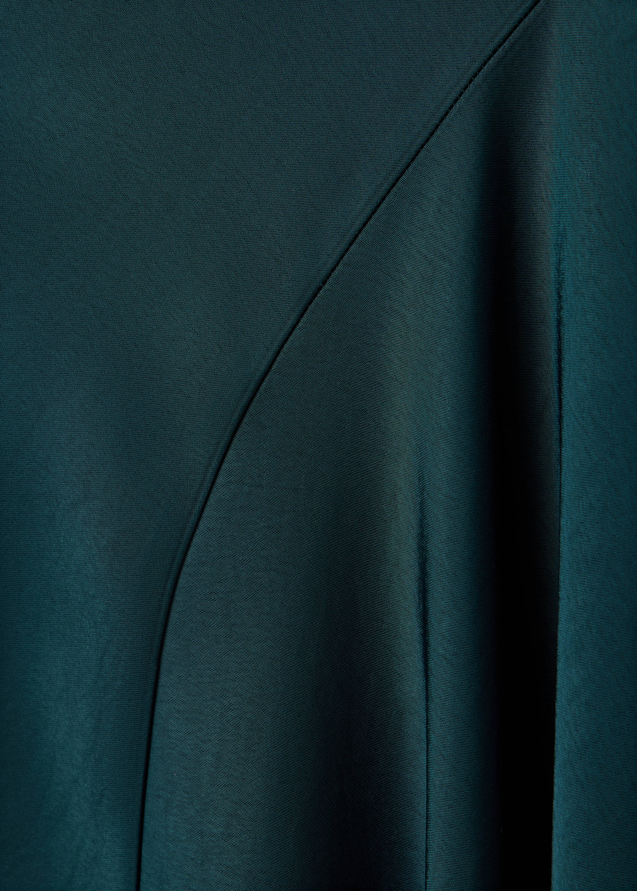 Dark green dress fabric detail showing satin texture and seam