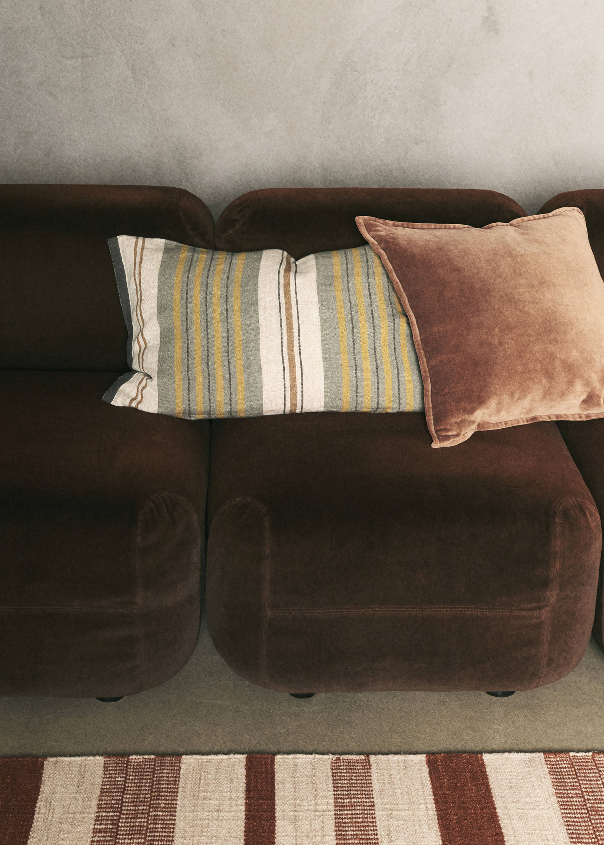 Rectangular striped cushion cover with green, yellow, and brown vertical lines.