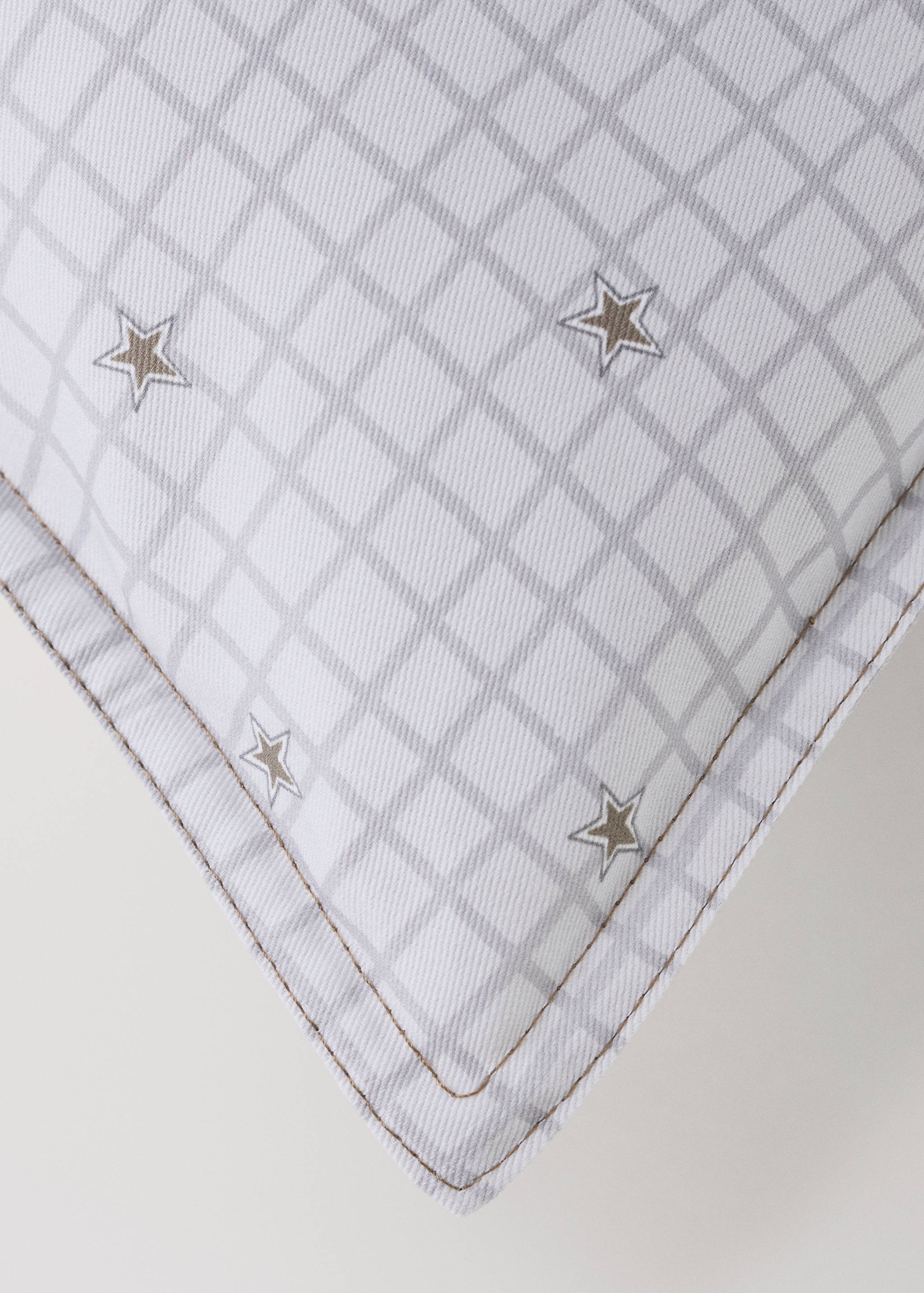 White cushion cover with grey grid pattern and embroidered stars.