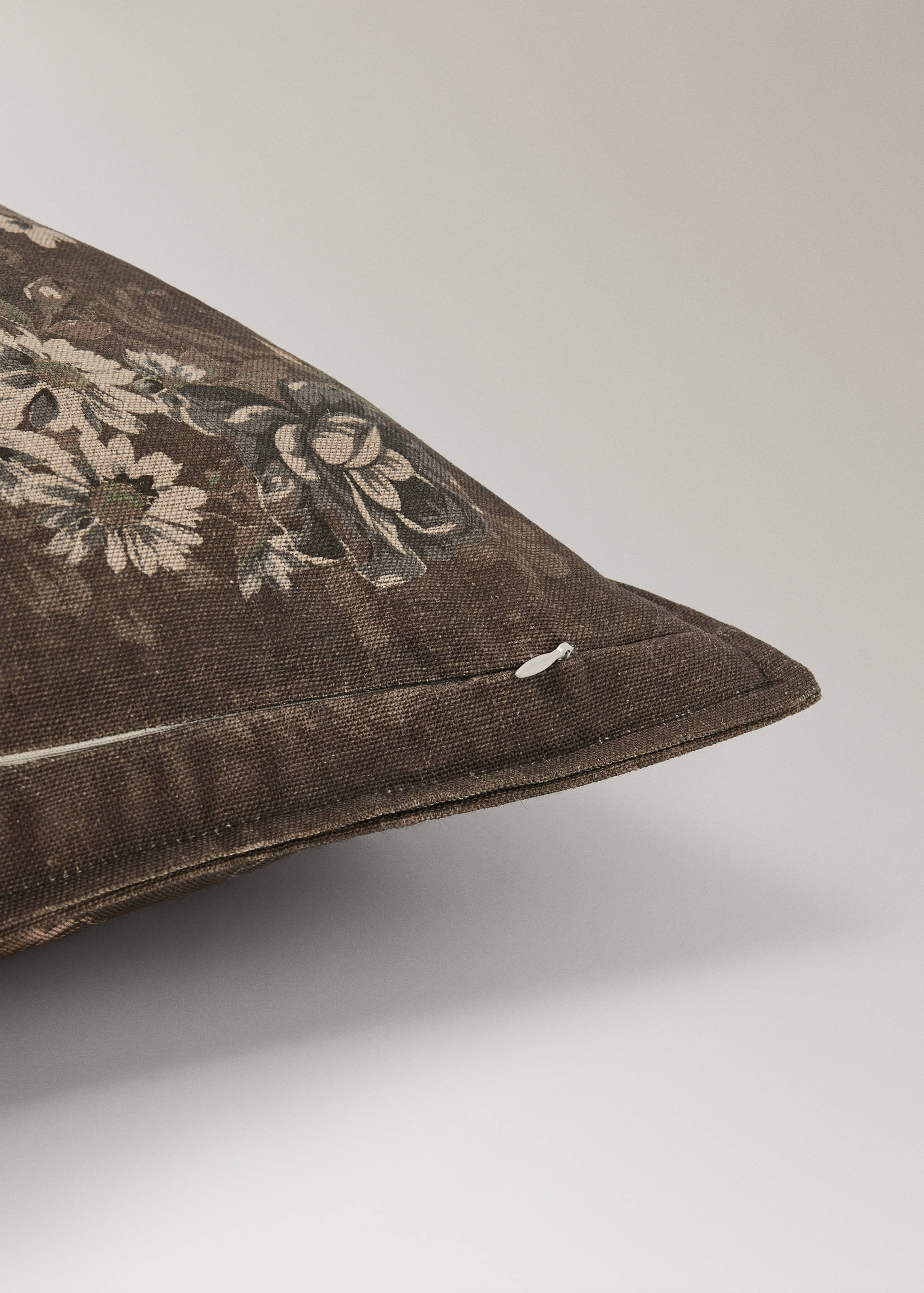 Close-up of a dark brown floral cushion cover with visible textured weave and zipper detail.