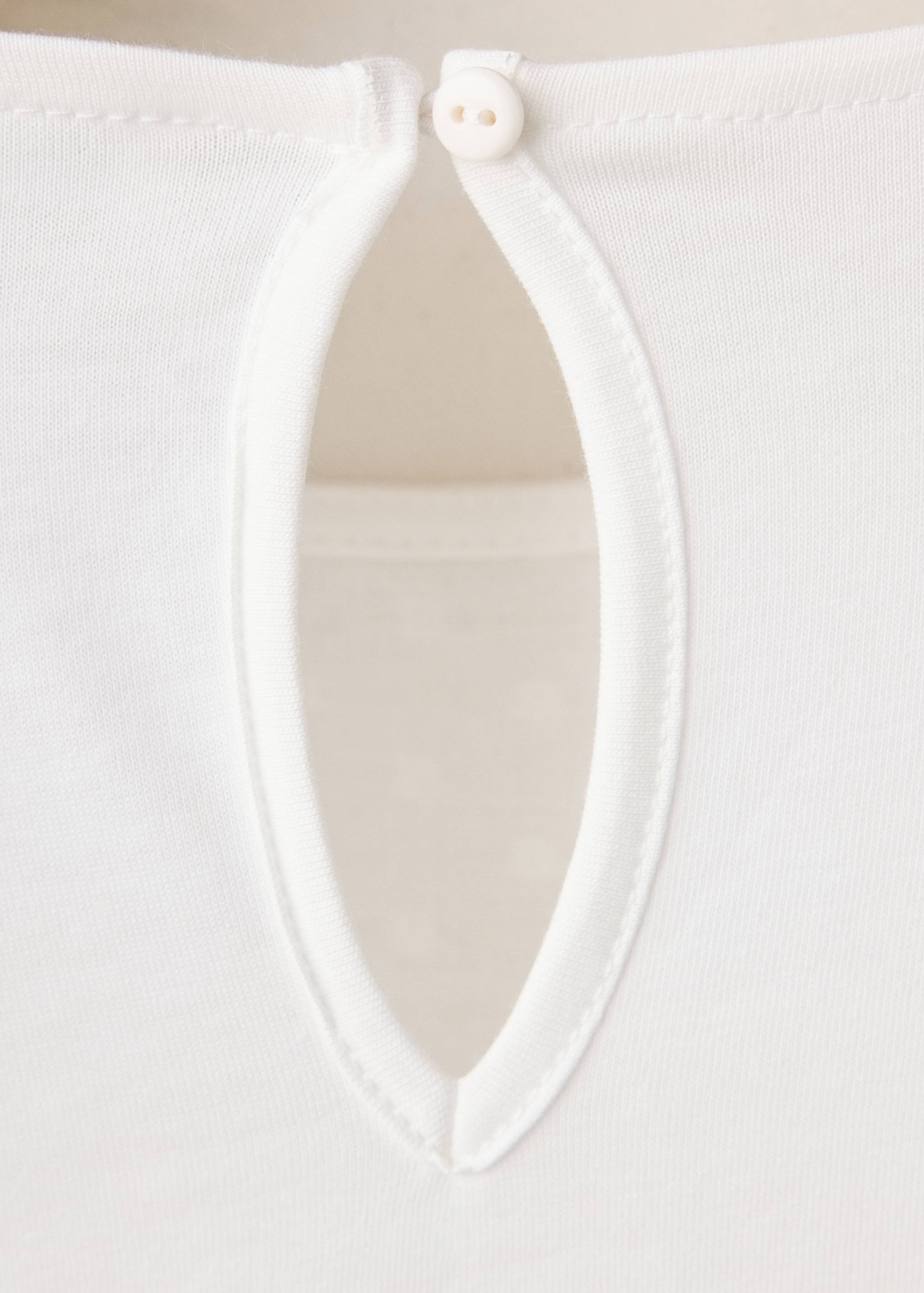 White kids' t-shirt close-up showing back keyhole neckline with button.