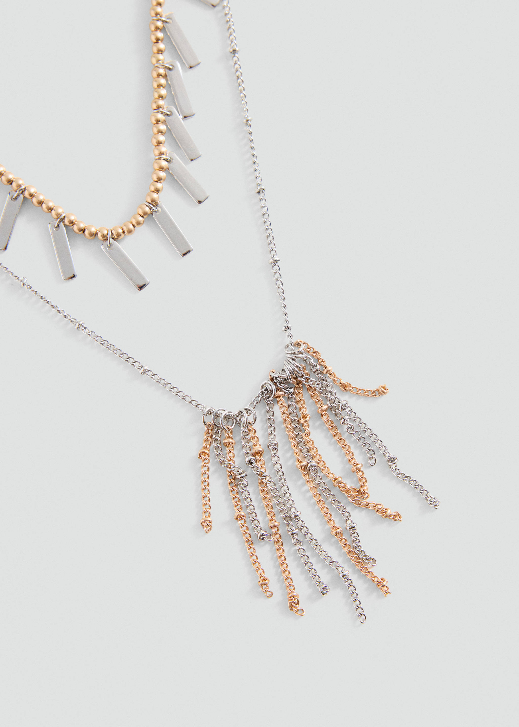 Layered gold and silver necklace with hanging rectangular bars and chain fringe.