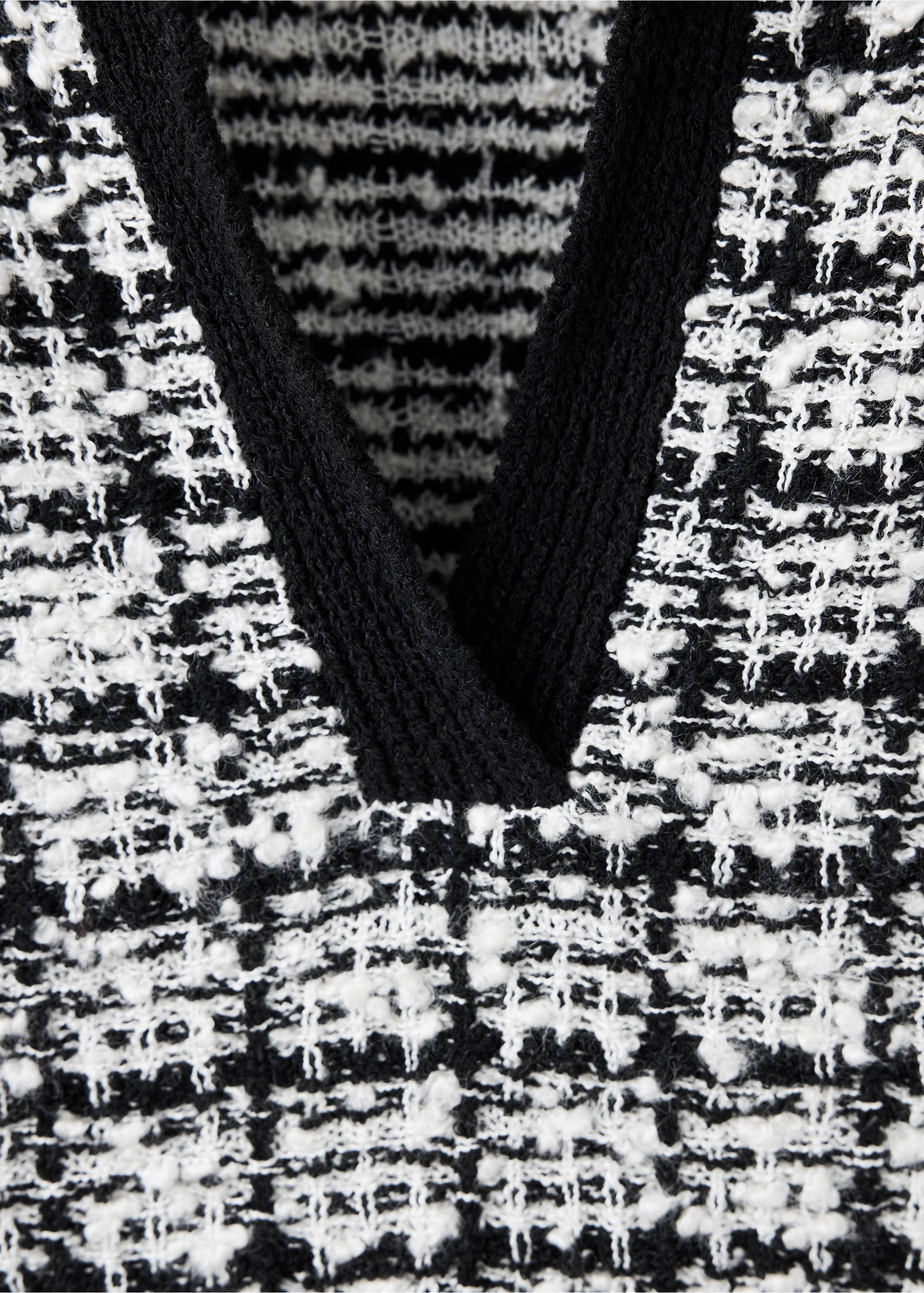 Close-up of a black and white patterned jersey with a solid black ribbed V-neck collar., Black. Ref: 37015892-00.