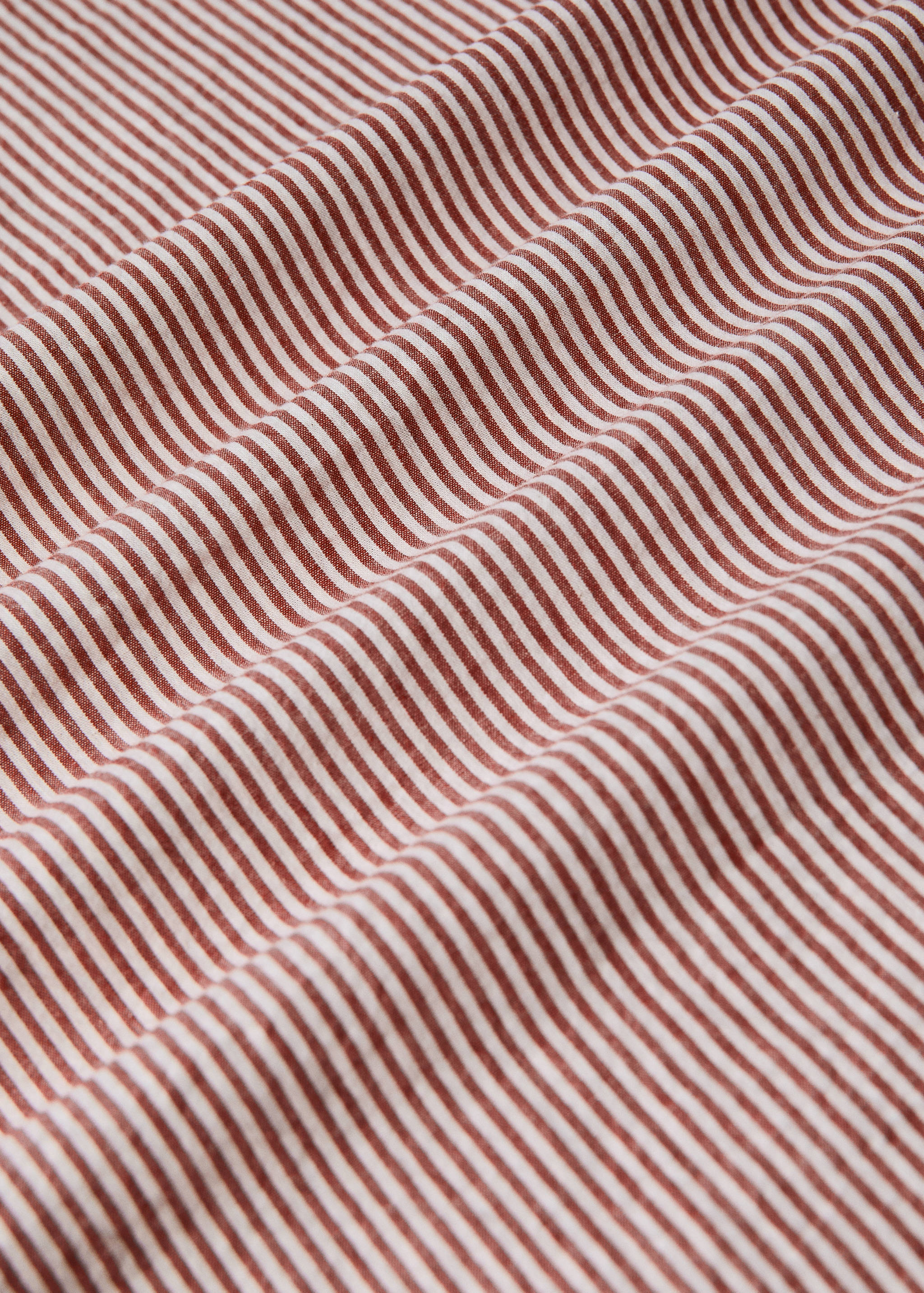 Close-up of a white and brownish-red striped duvet cover.