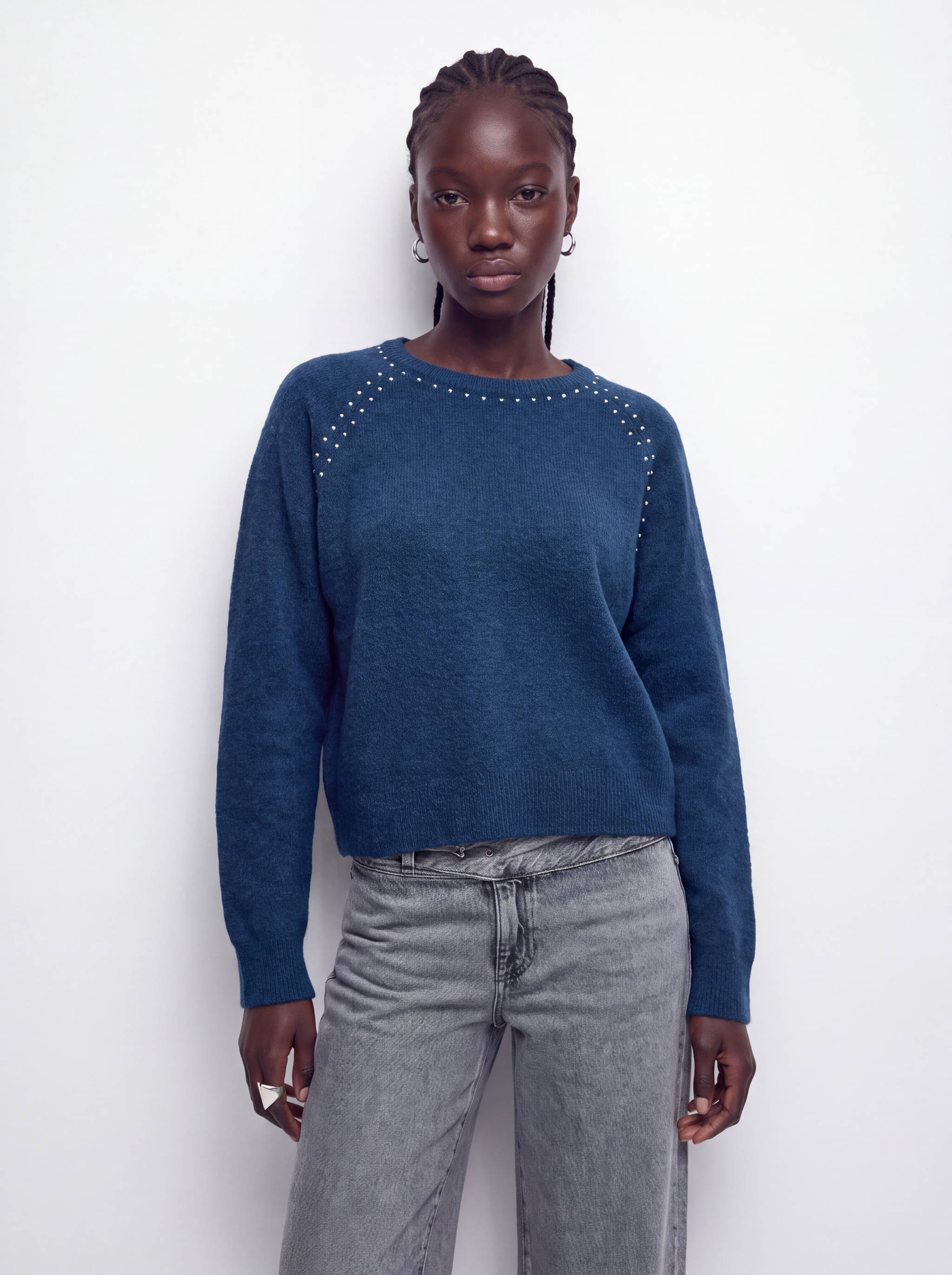 Dark blue knitted jersey with studded neckline and long sleeves.