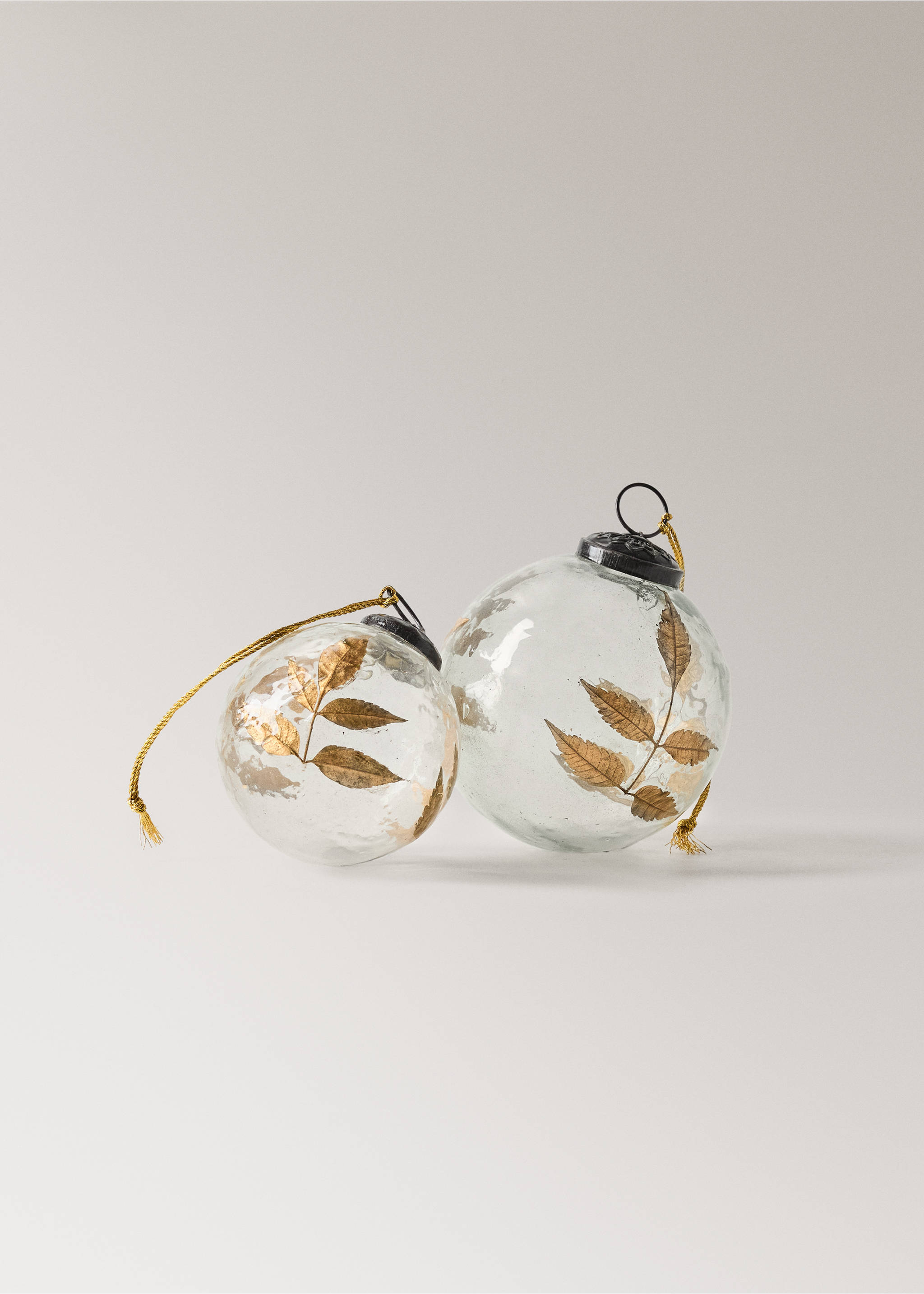 Two clear glass Christmas baubles containing gold metallic leaf details, with dark caps and gold hanging cords., Gold. Ref: 37016731-00.