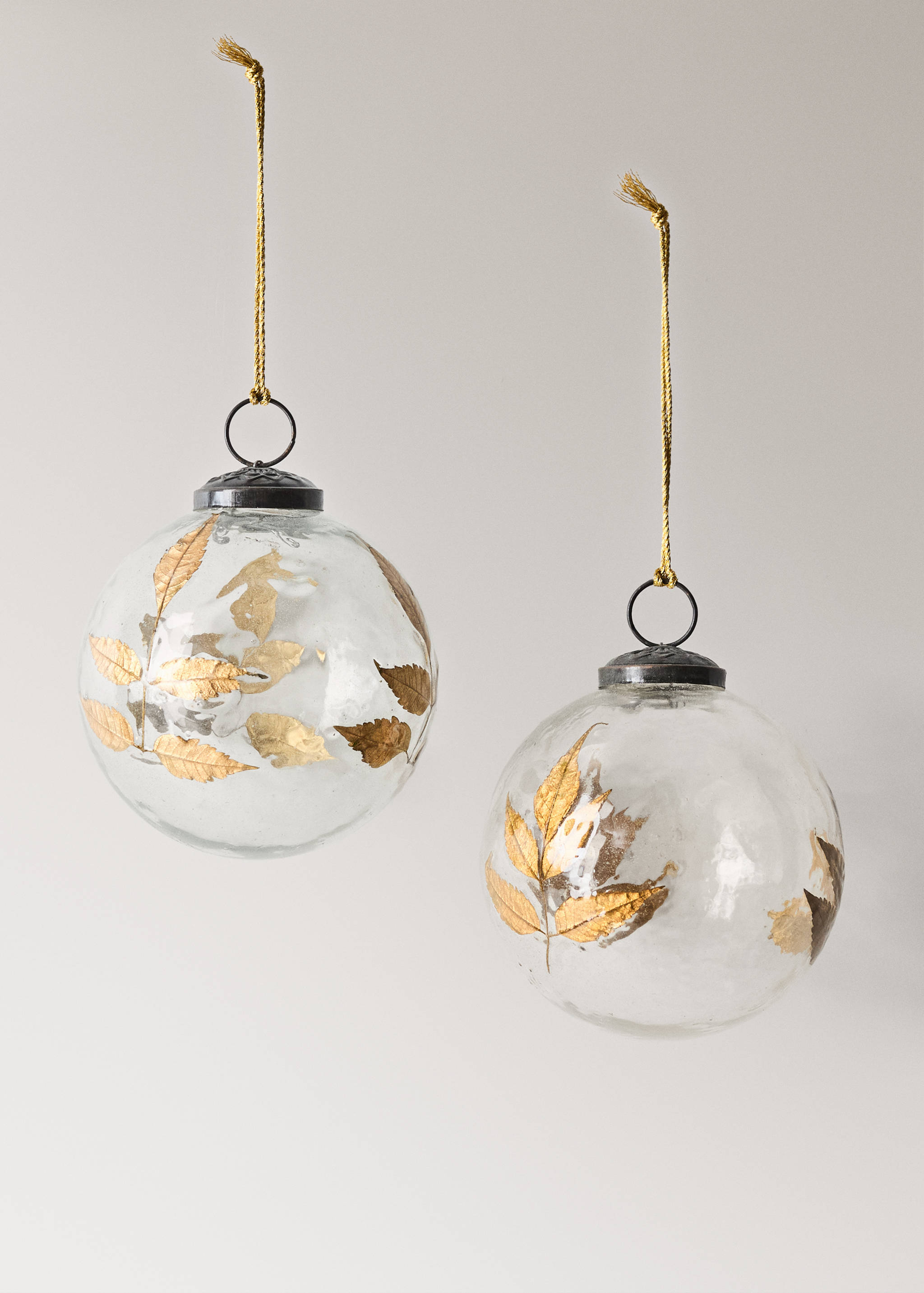 Two clear glass Christmas ornaments decorated with gold leaf leaves.