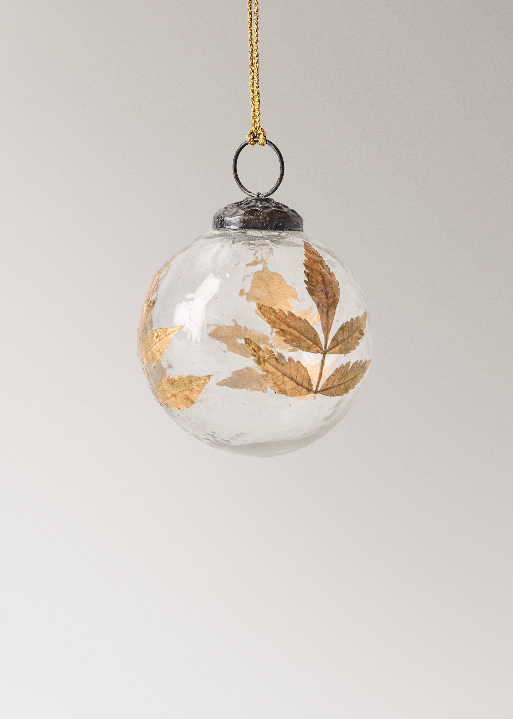Clear glass Christmas ornament with pressed golden leaves inside.