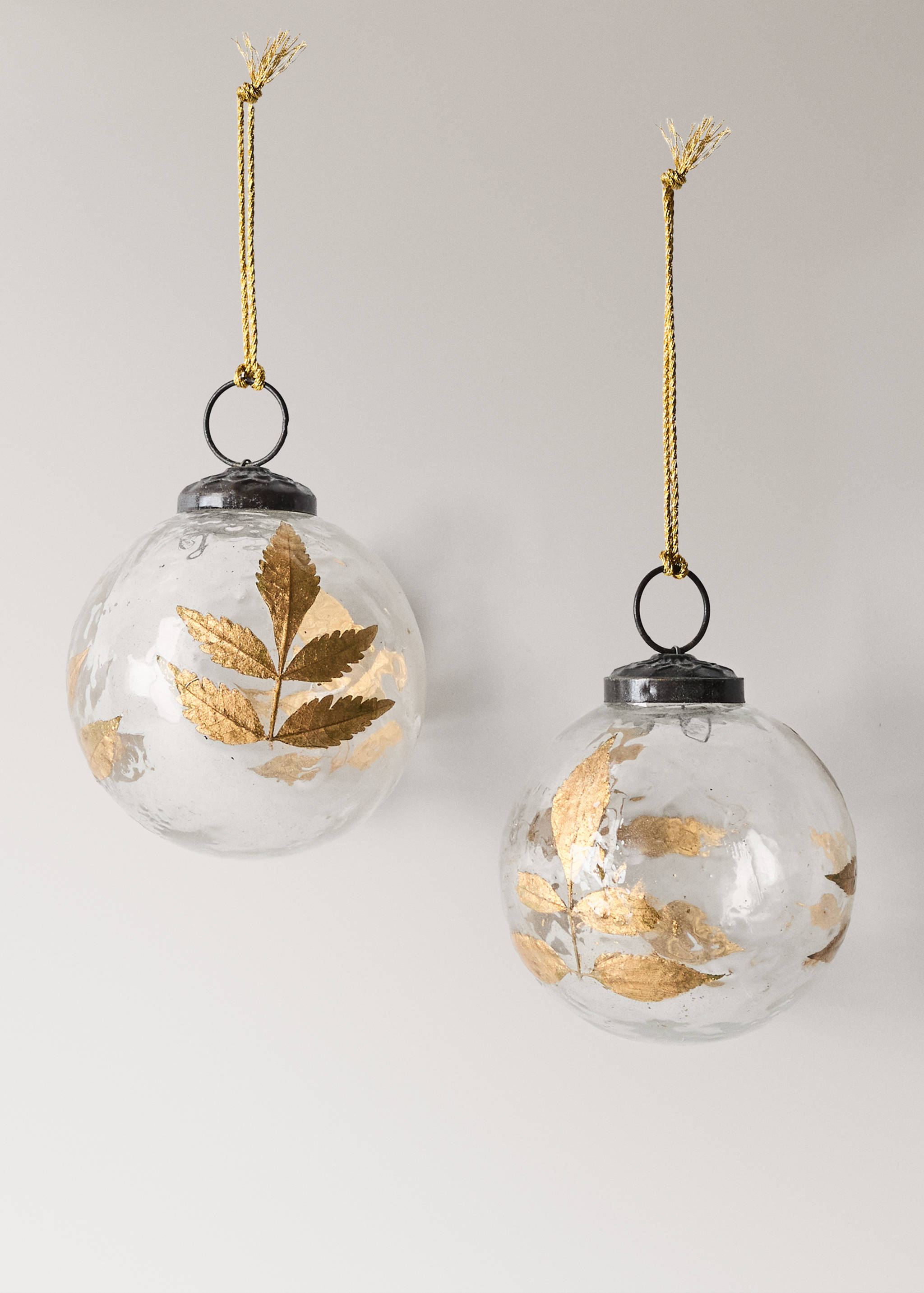Two round glass Christmas ornaments with gold leaf motifs and metallic caps.