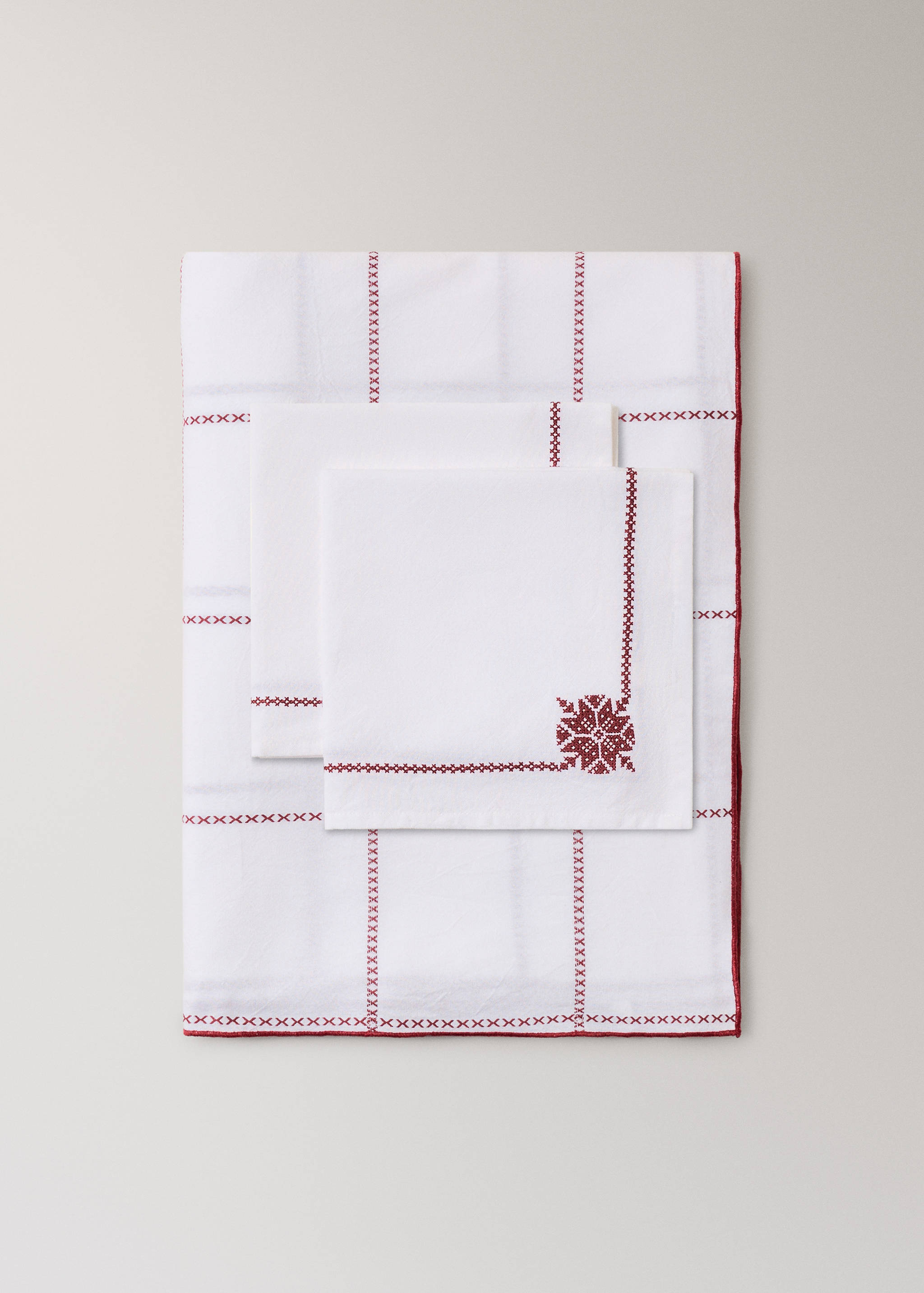 Mantel y servilletas de color blanco con bordado de punto de cruz en rojo.