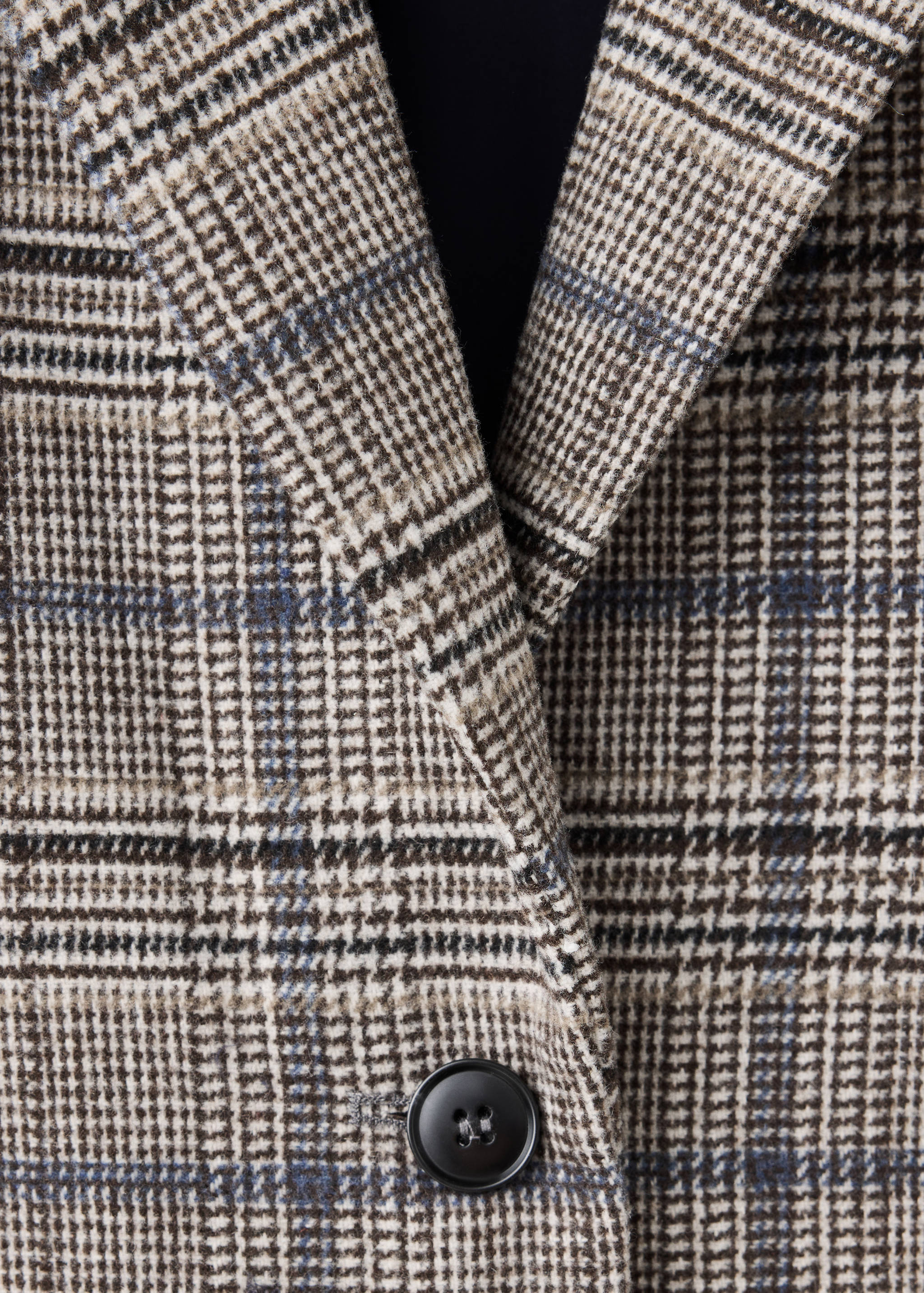 Close-up of a brown and cream plaid coat detail.