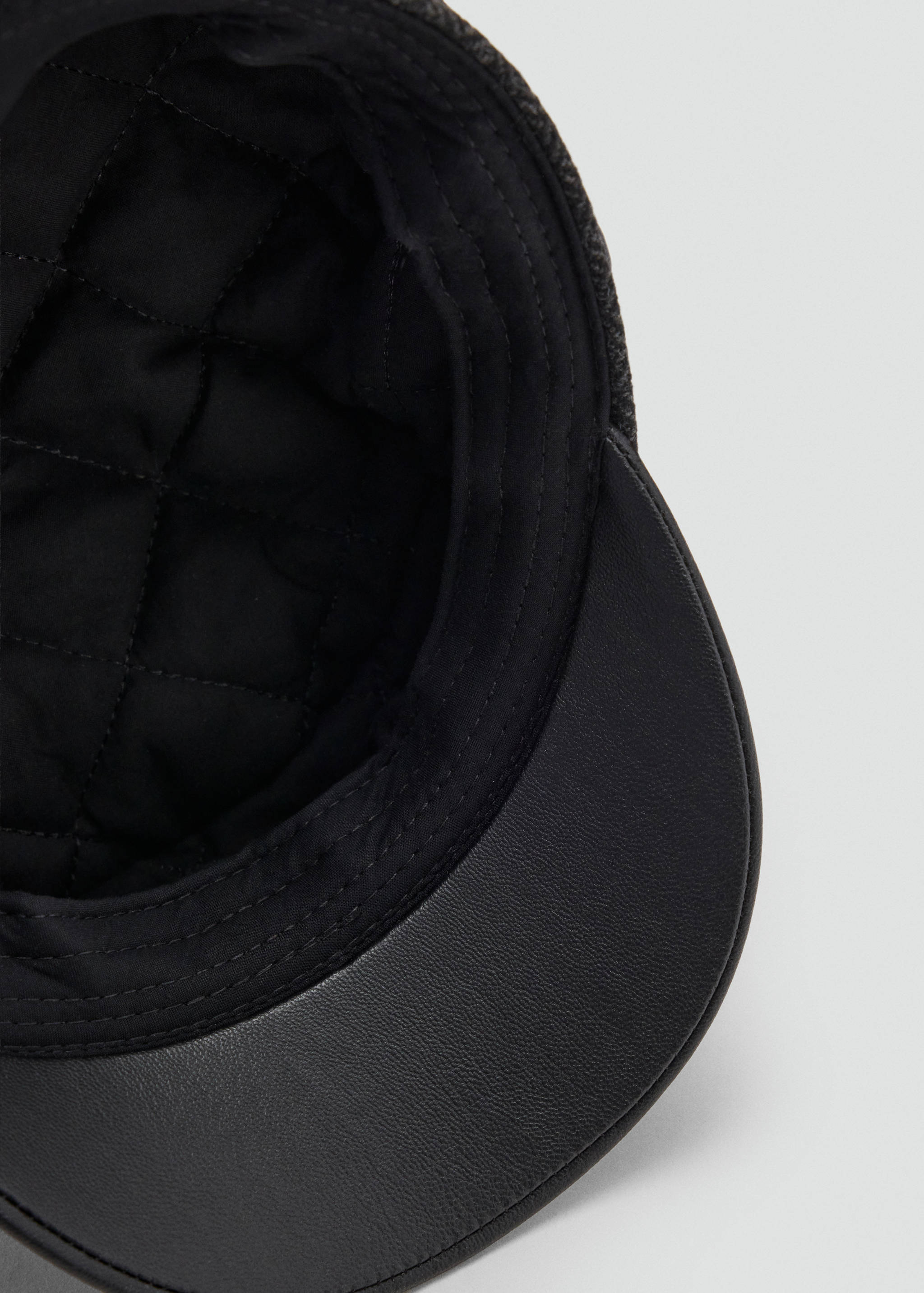 Close-up of the quilted inner lining of a black cap.