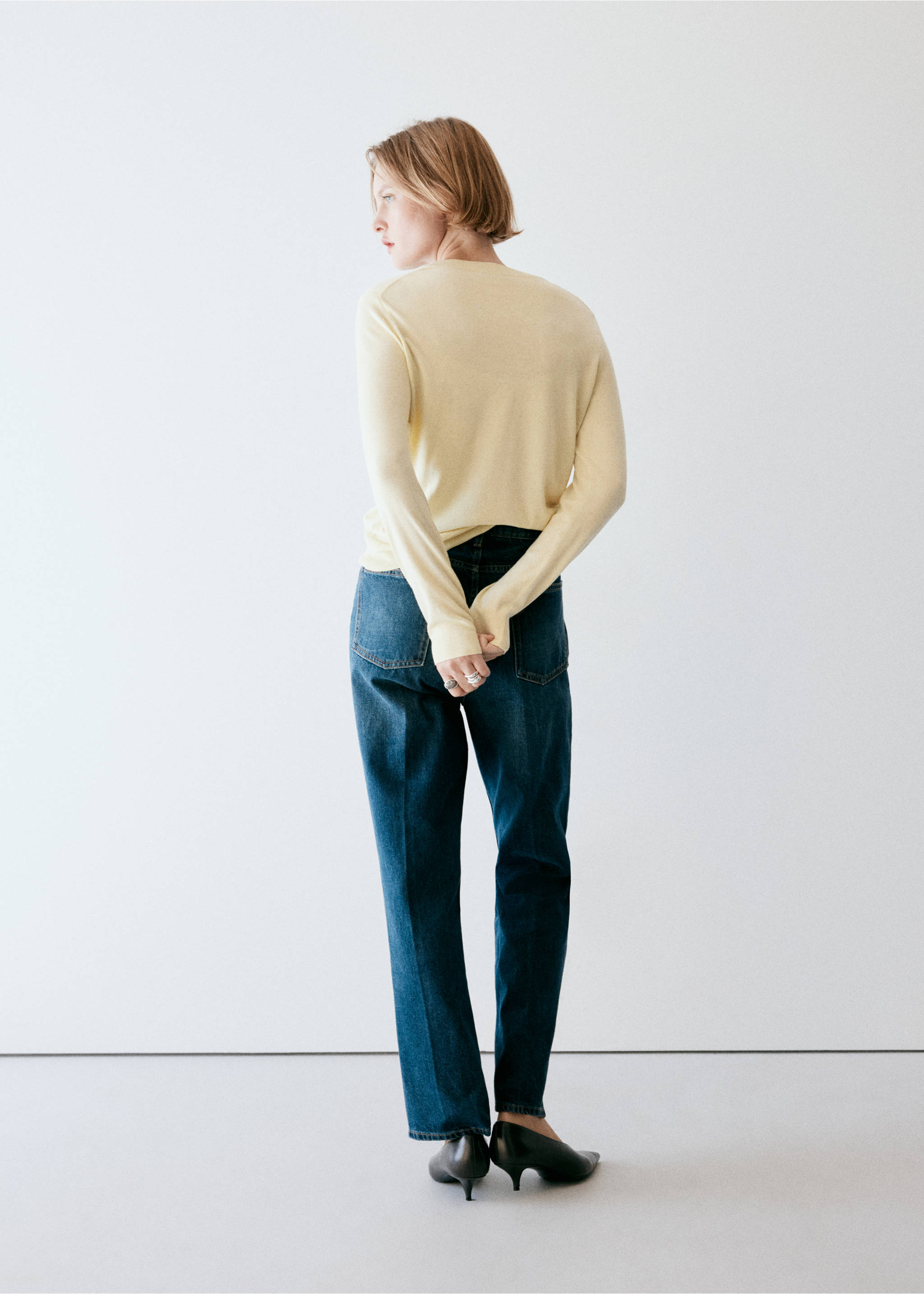 Back view of a light yellow long-sleeved jersey sweater worn with blue trousers., Pastel Yellow. Ref: 37017777-00.