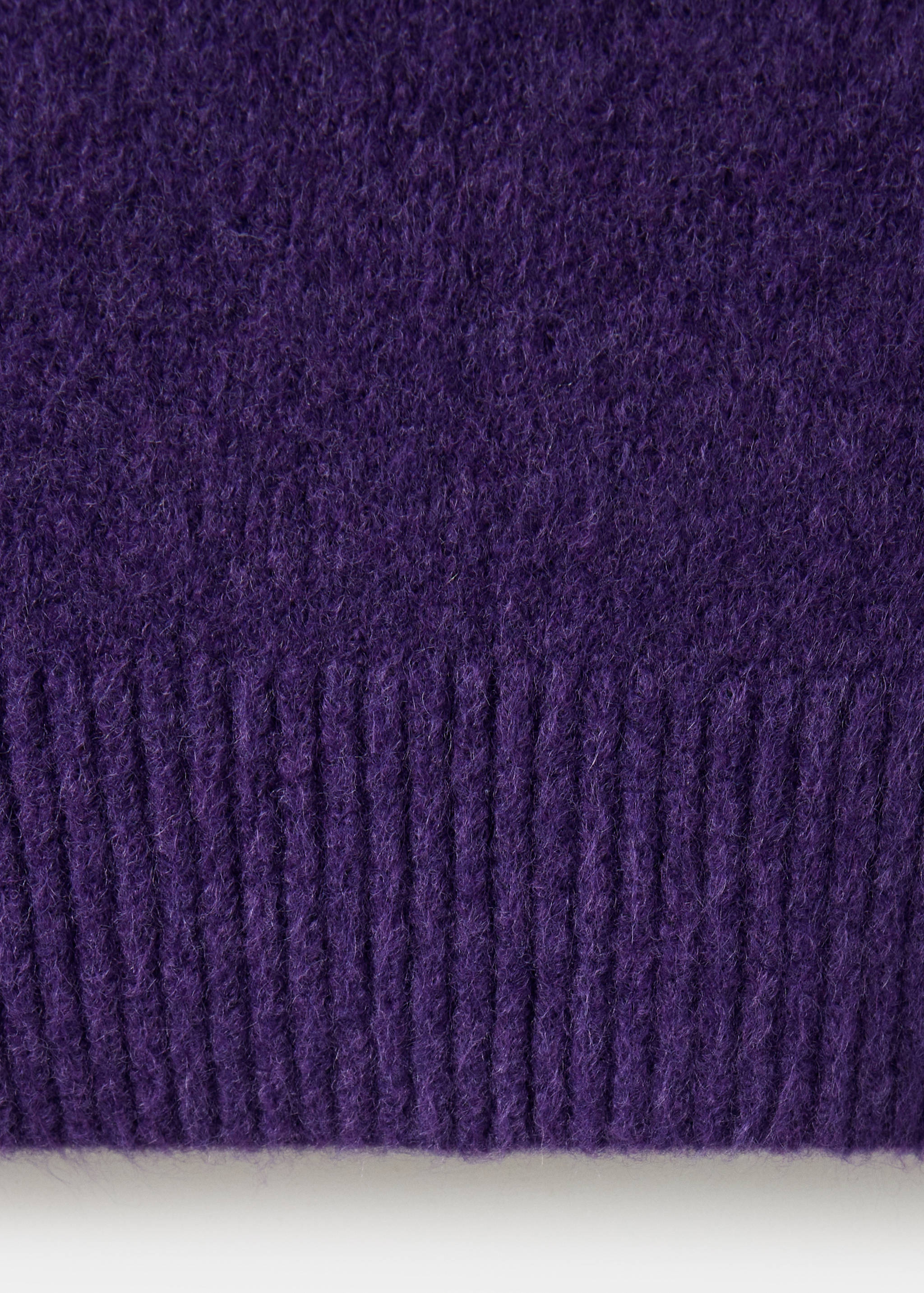 Close-up of the fuzzy purple knit fabric and ribbed hem of a jumper.