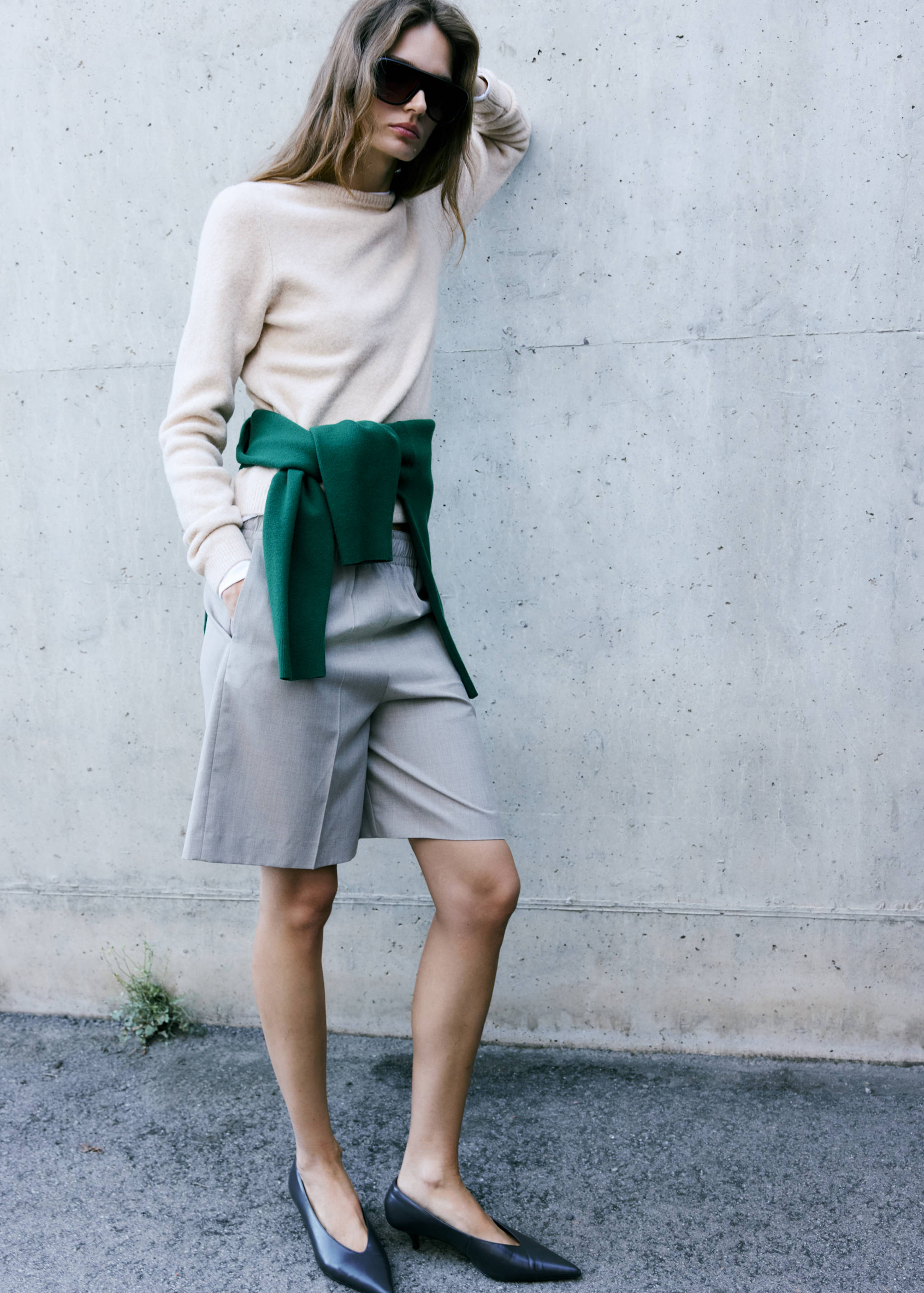 Cream knitted jumper styled with a green jumper tied around the waist.