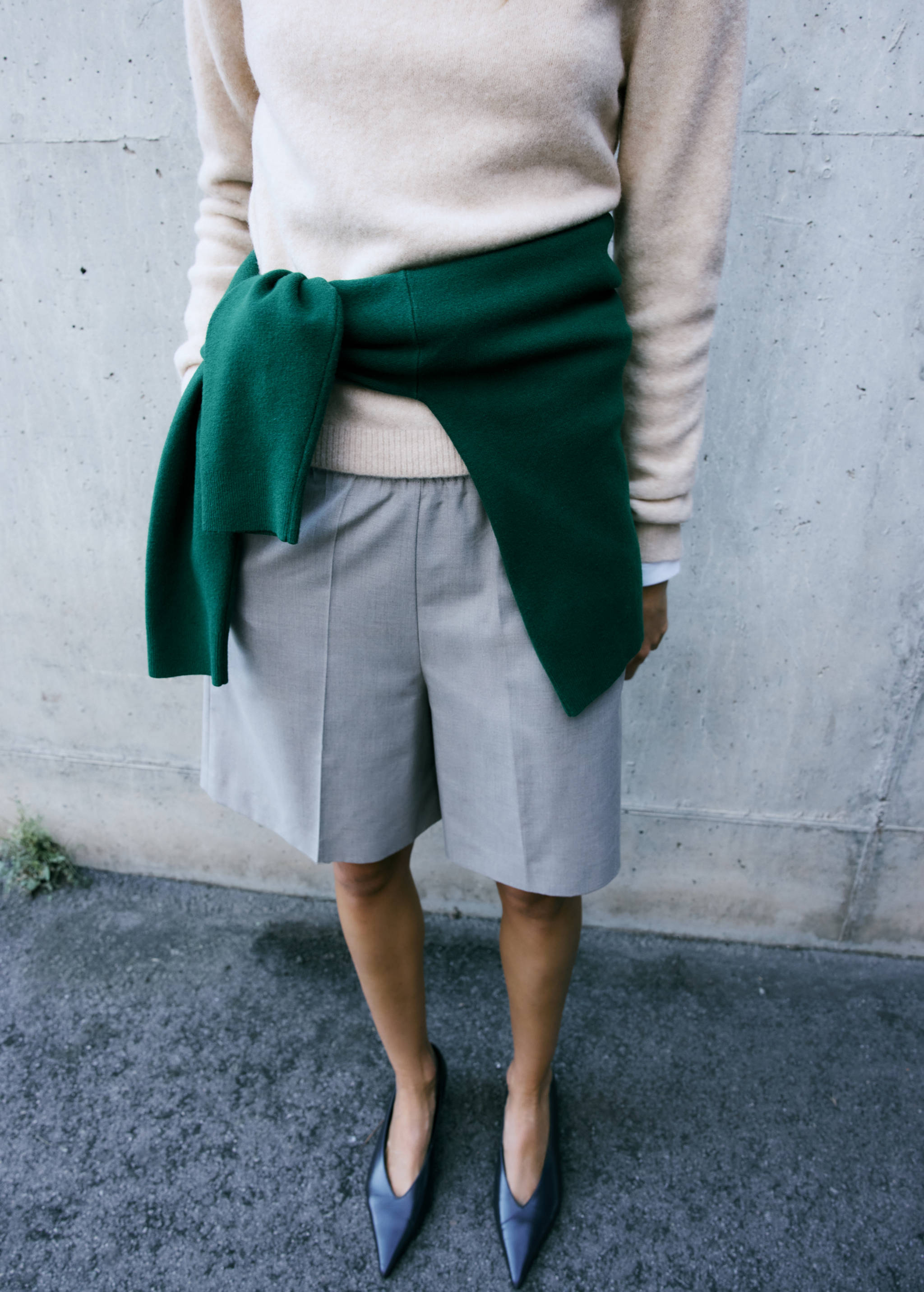 Beige knitted jersey with a dark green sweater tied at the waist.