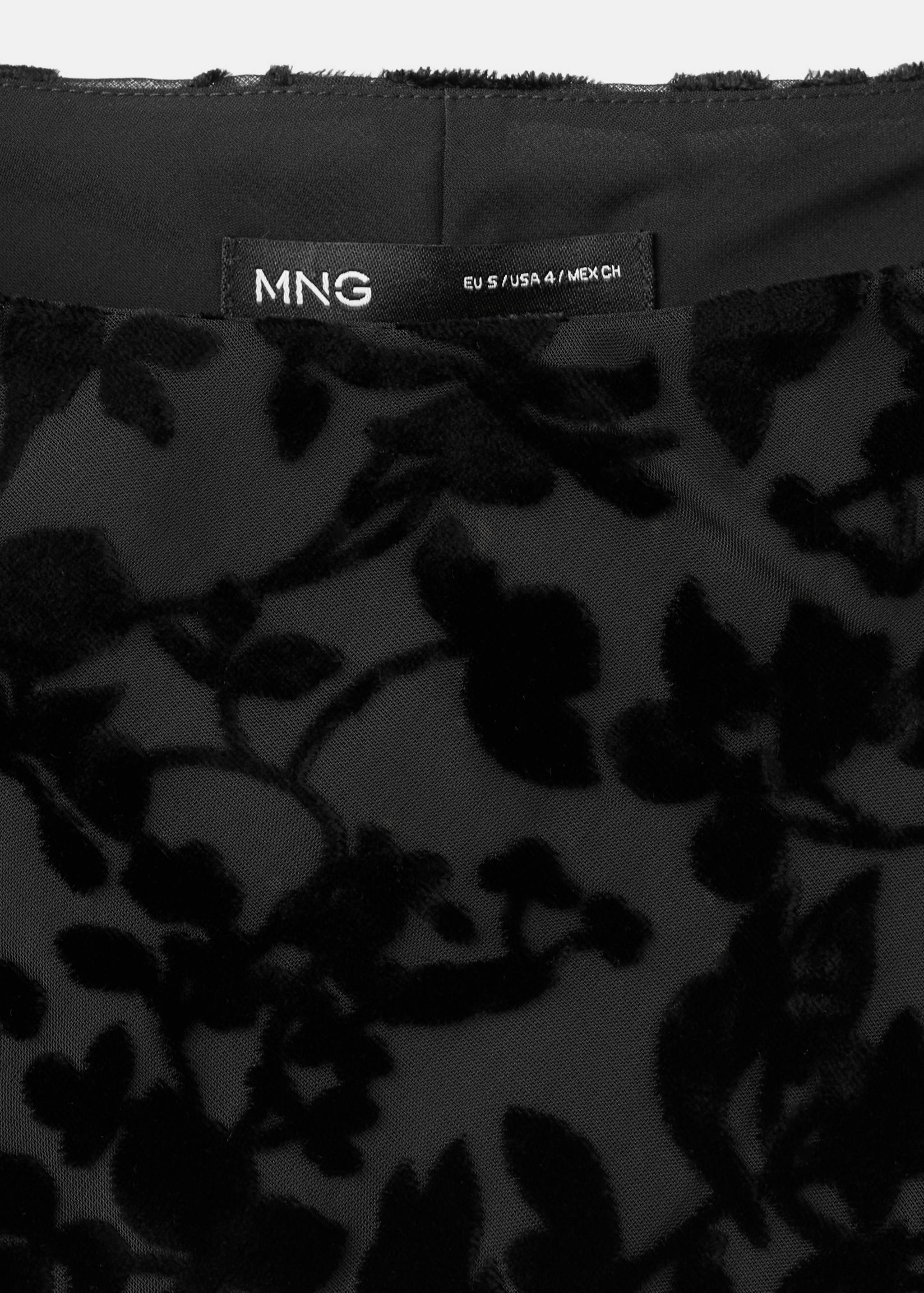 Close-up of the black dress label and floral velvet fabric.