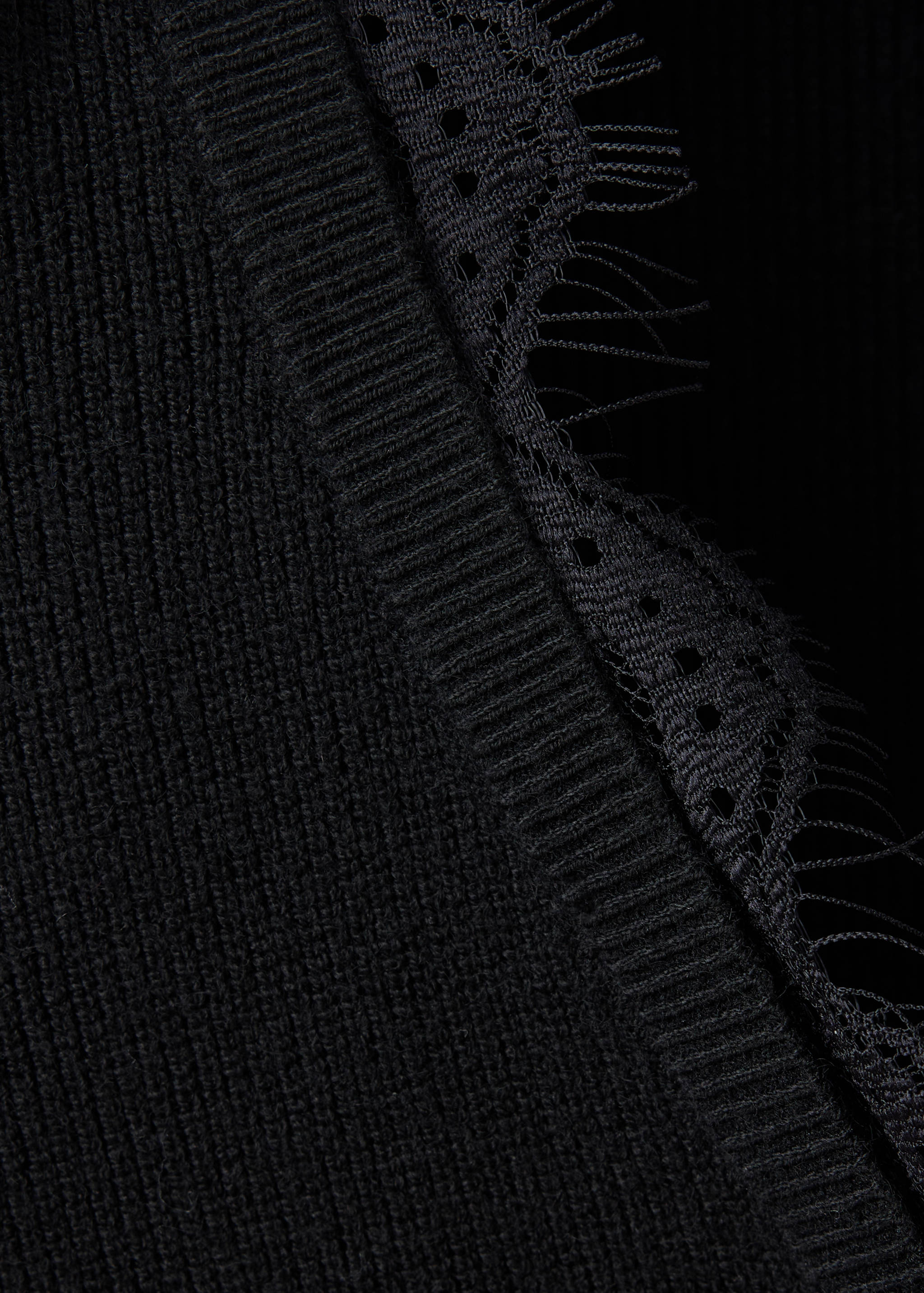 Close-up of a black knitted sweater with lace trim.