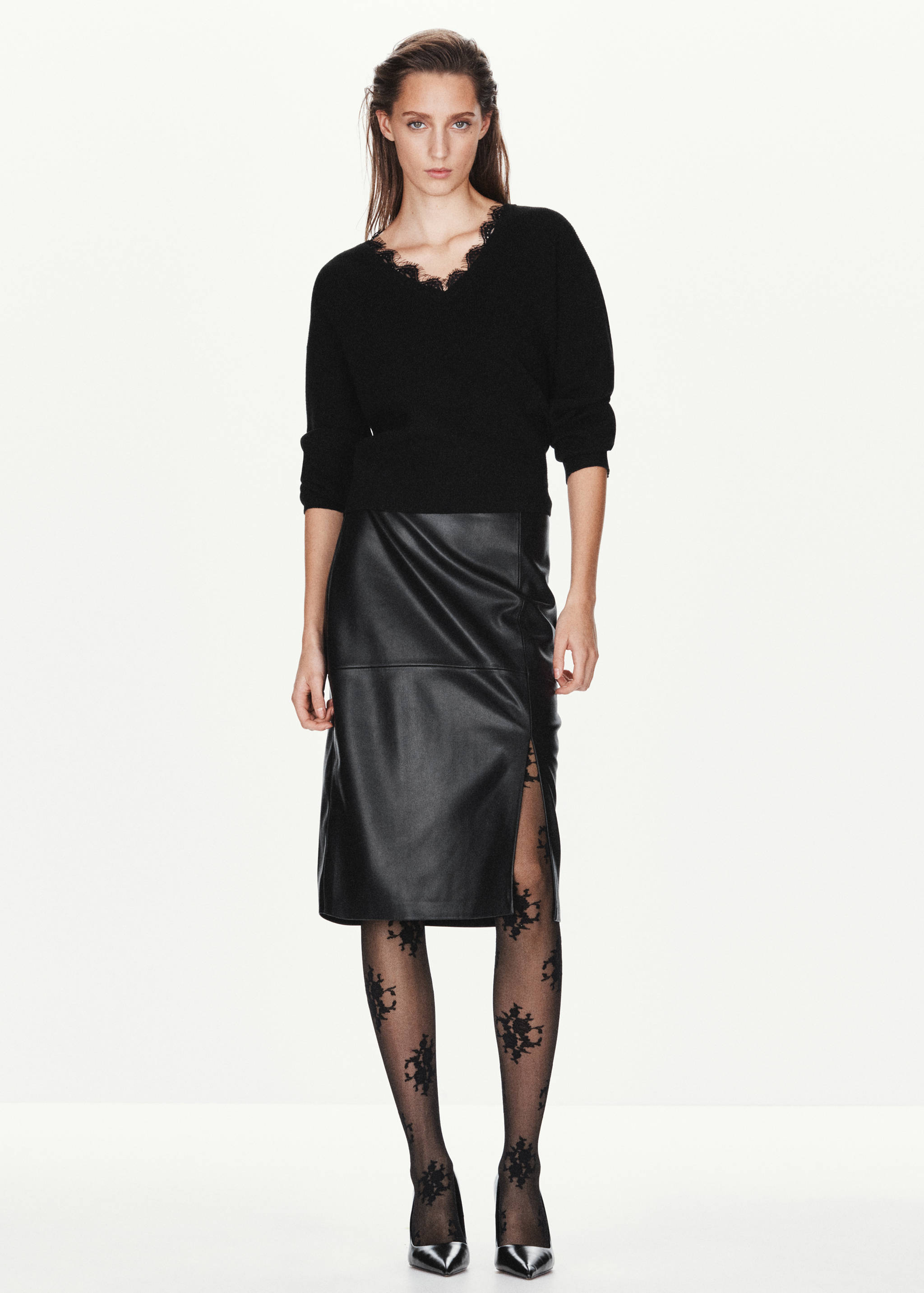 Black knit jumper with lace-trimmed V-neck, worn with a faux-leather skirt.