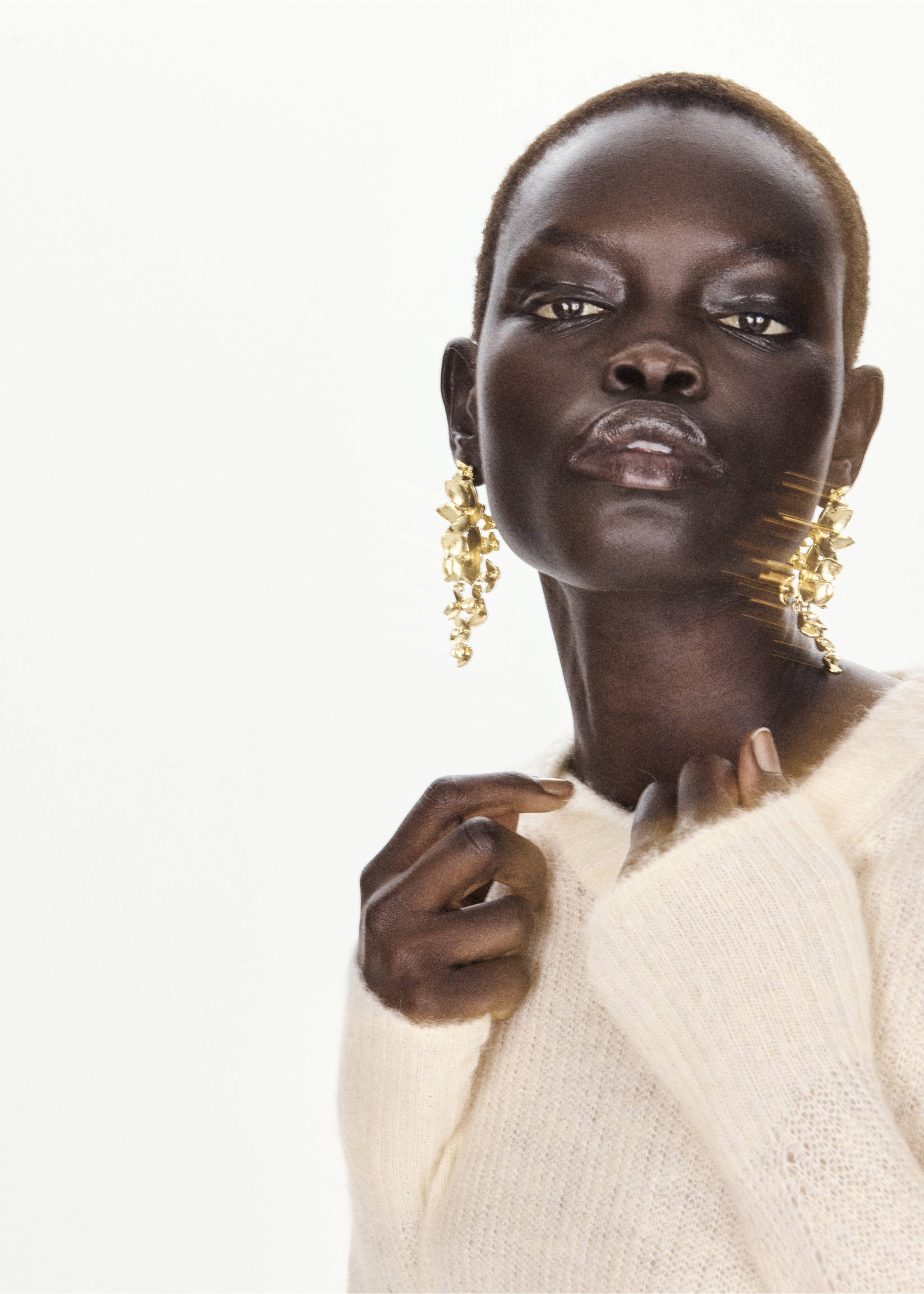 Close-up of a model wearing a cream-coloured knit sweater and ornate gold earrings., Ecru. Ref: 37017791-00.