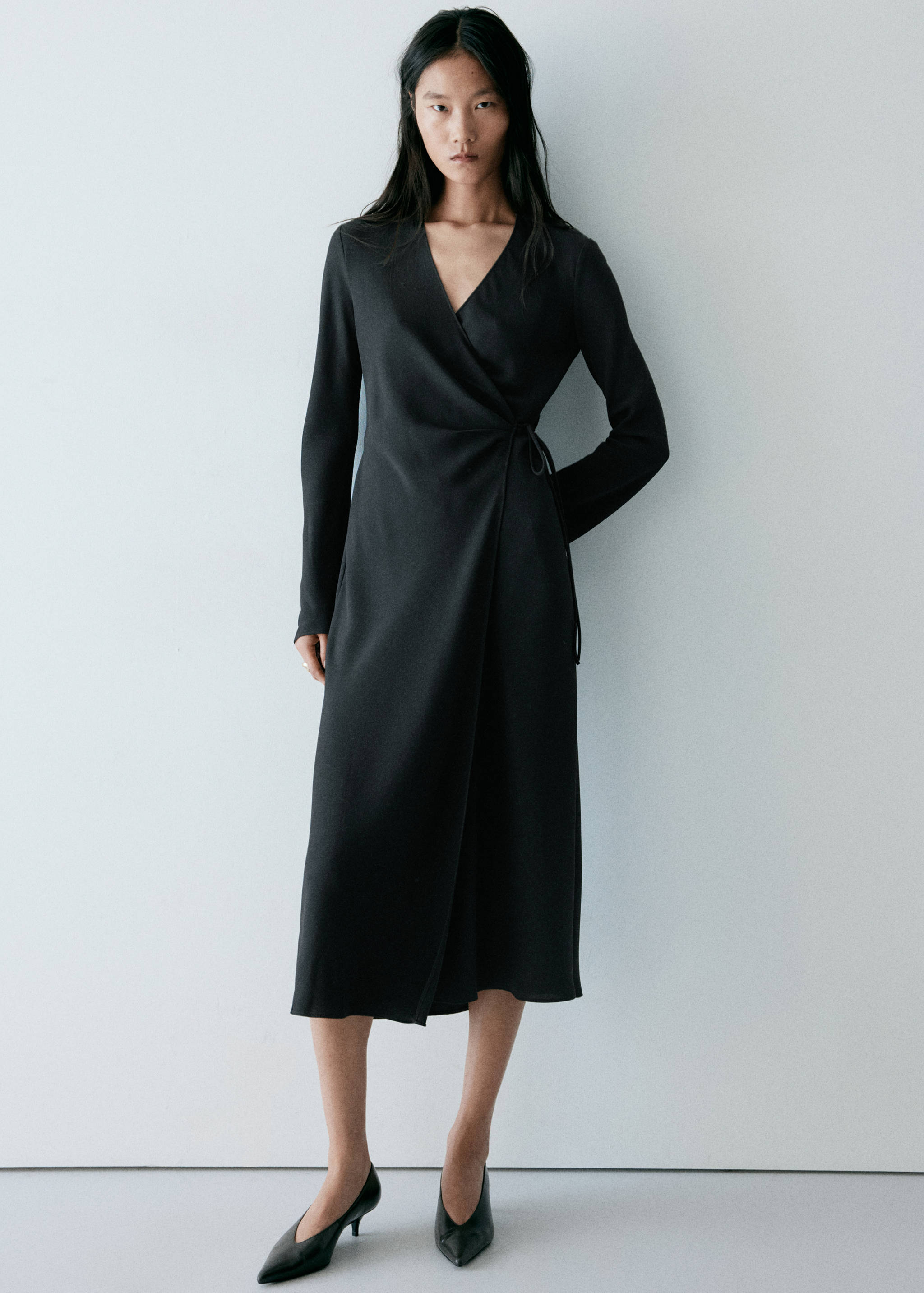 Vestido midi cruzado negro de manga larga con cuello en V y lazada lateral.