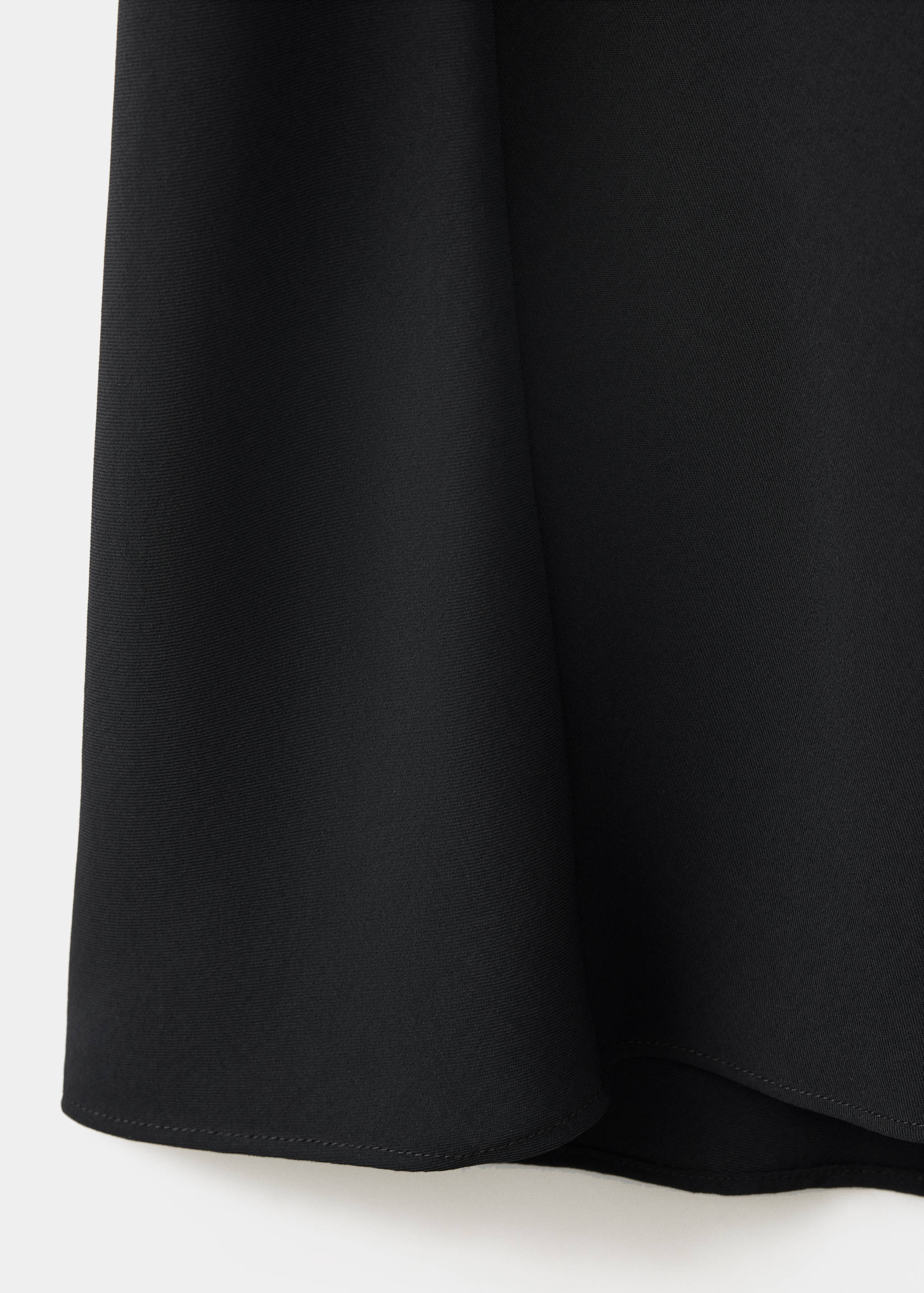 Detalle del tejido negro y liso del vestido.