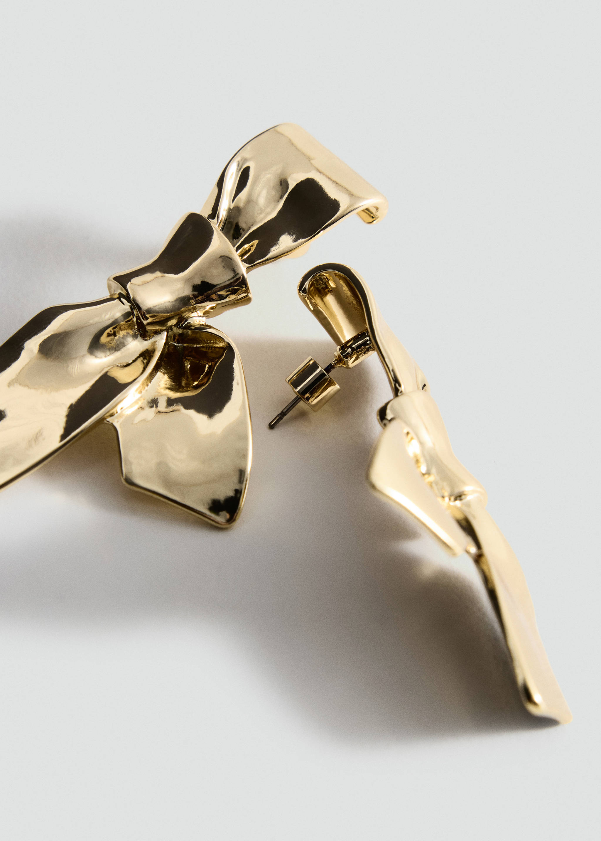 Gold-coloured metallic bow earrings in a sculpted design.