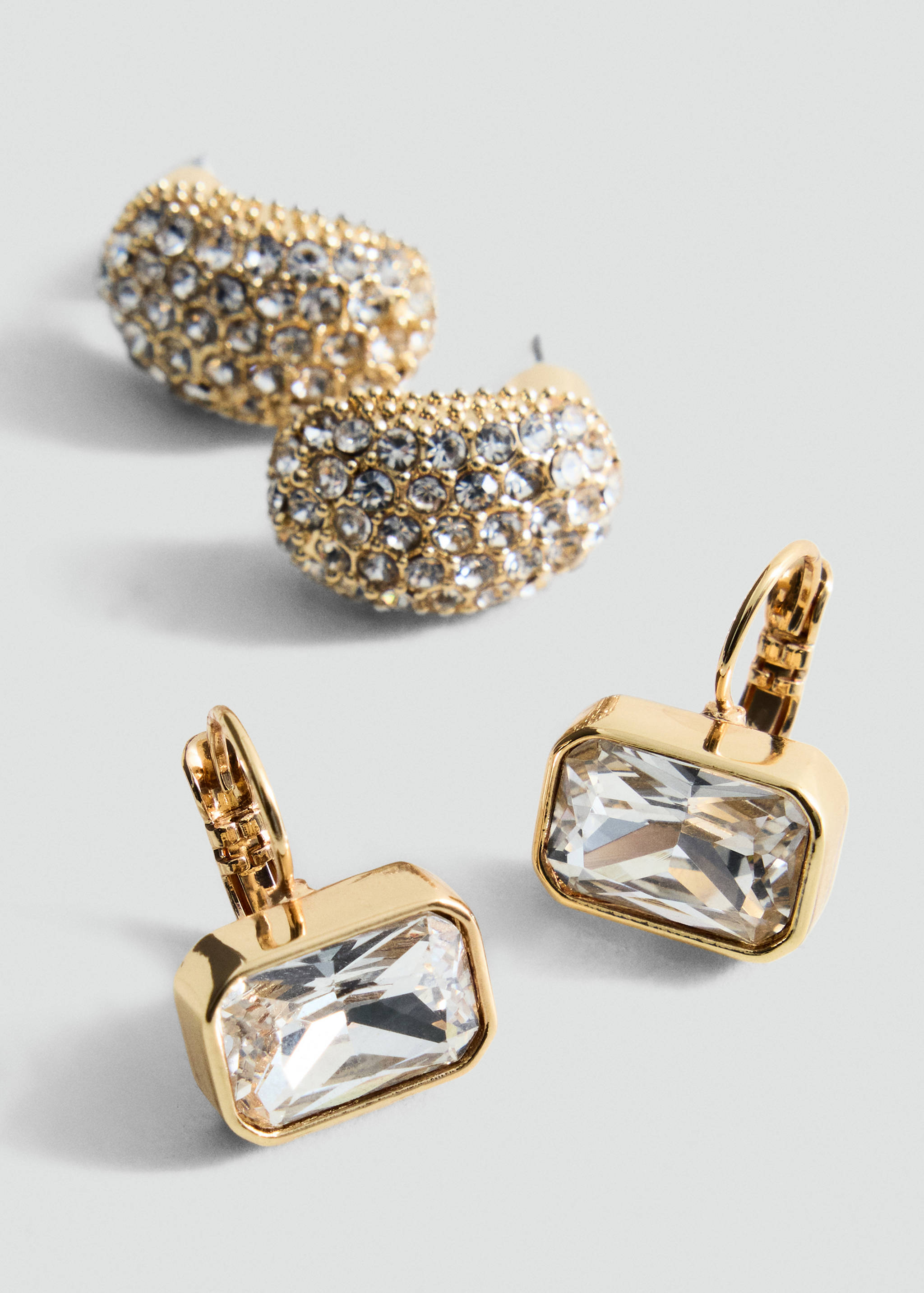 Gold-toned earrings with rectangular faceted clear crystals and hinged clasps.